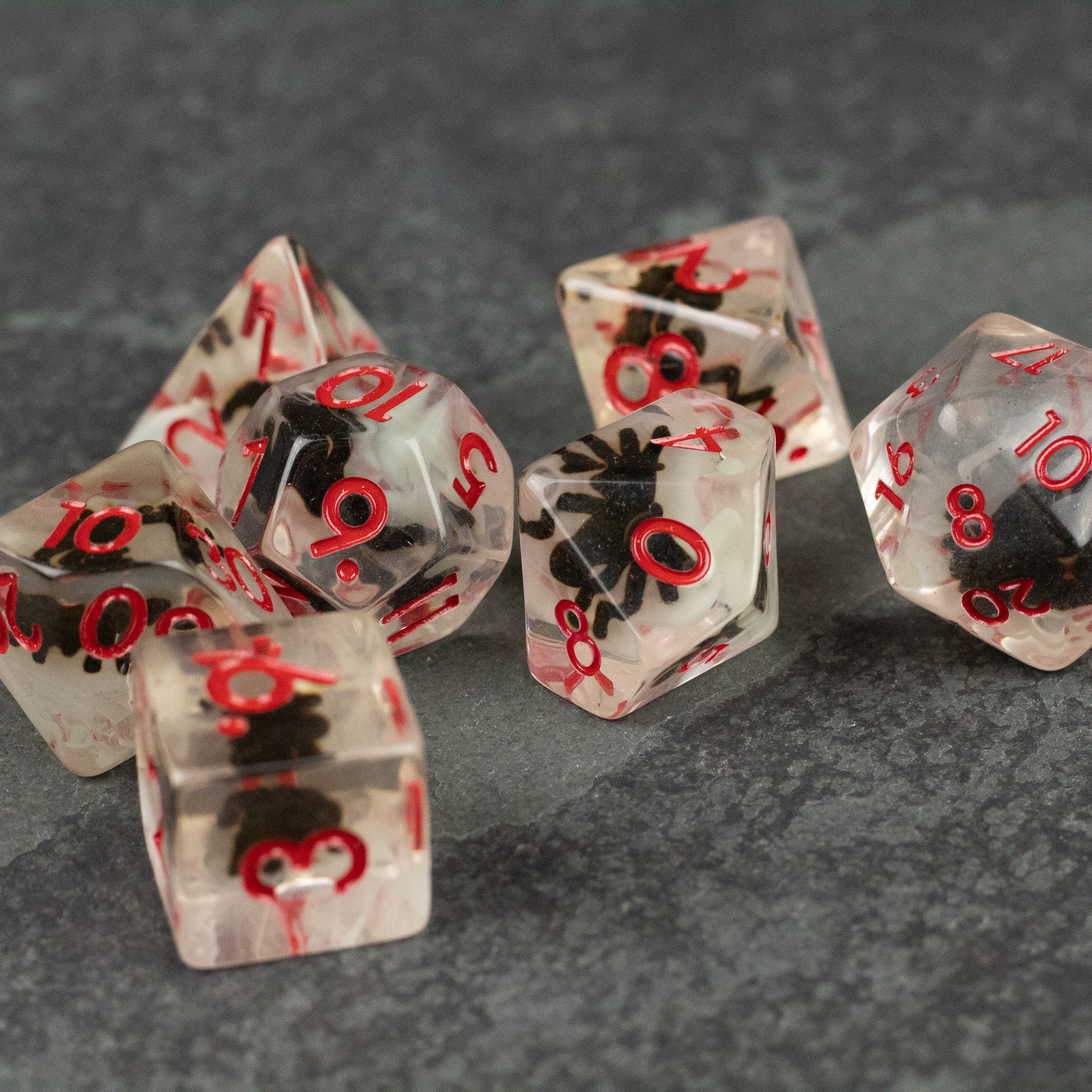 Black Spider Dice Set - White - Clear polyhedral dice set with black spider inclusions and red numbers.