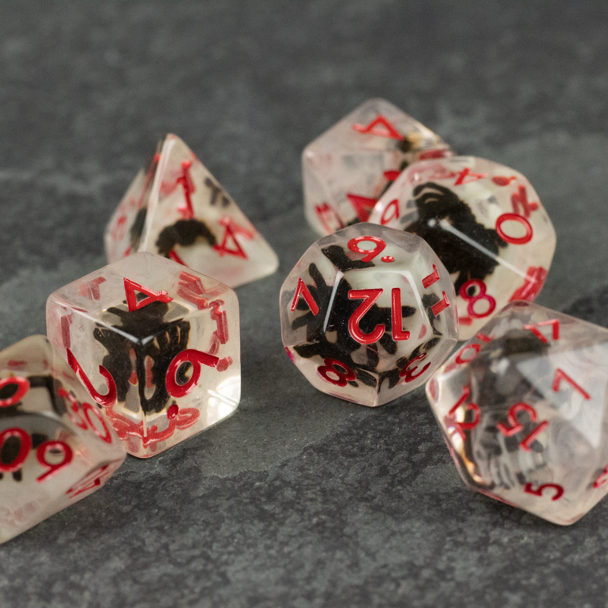 Black Spider Dice Set - White - Transparent polyhedral dice set with red numbers and black spider illustrations inside each die.