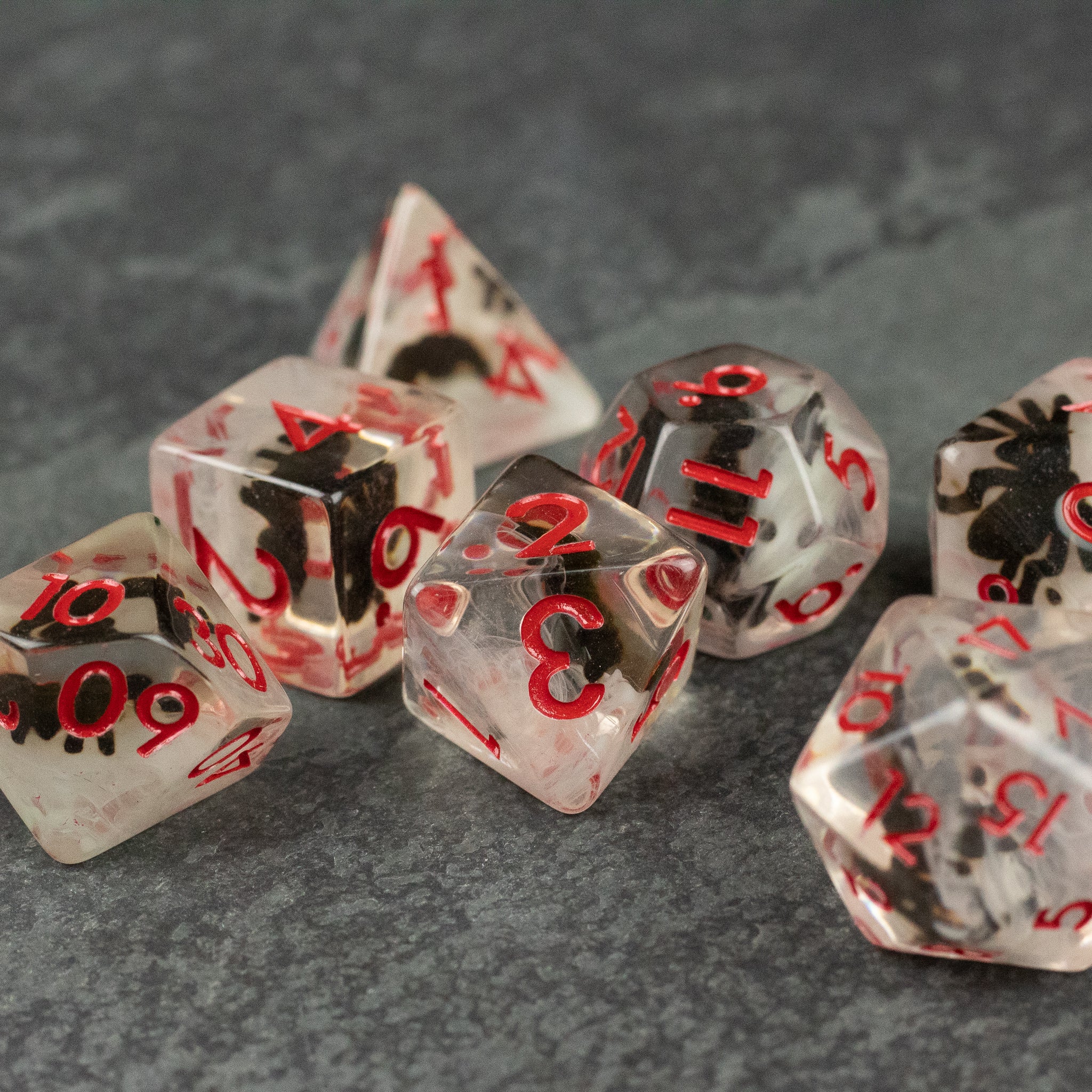 Black Spider Dice Set - White - Clear polyhedral dice set with red numbers and black spider designs inside each die.