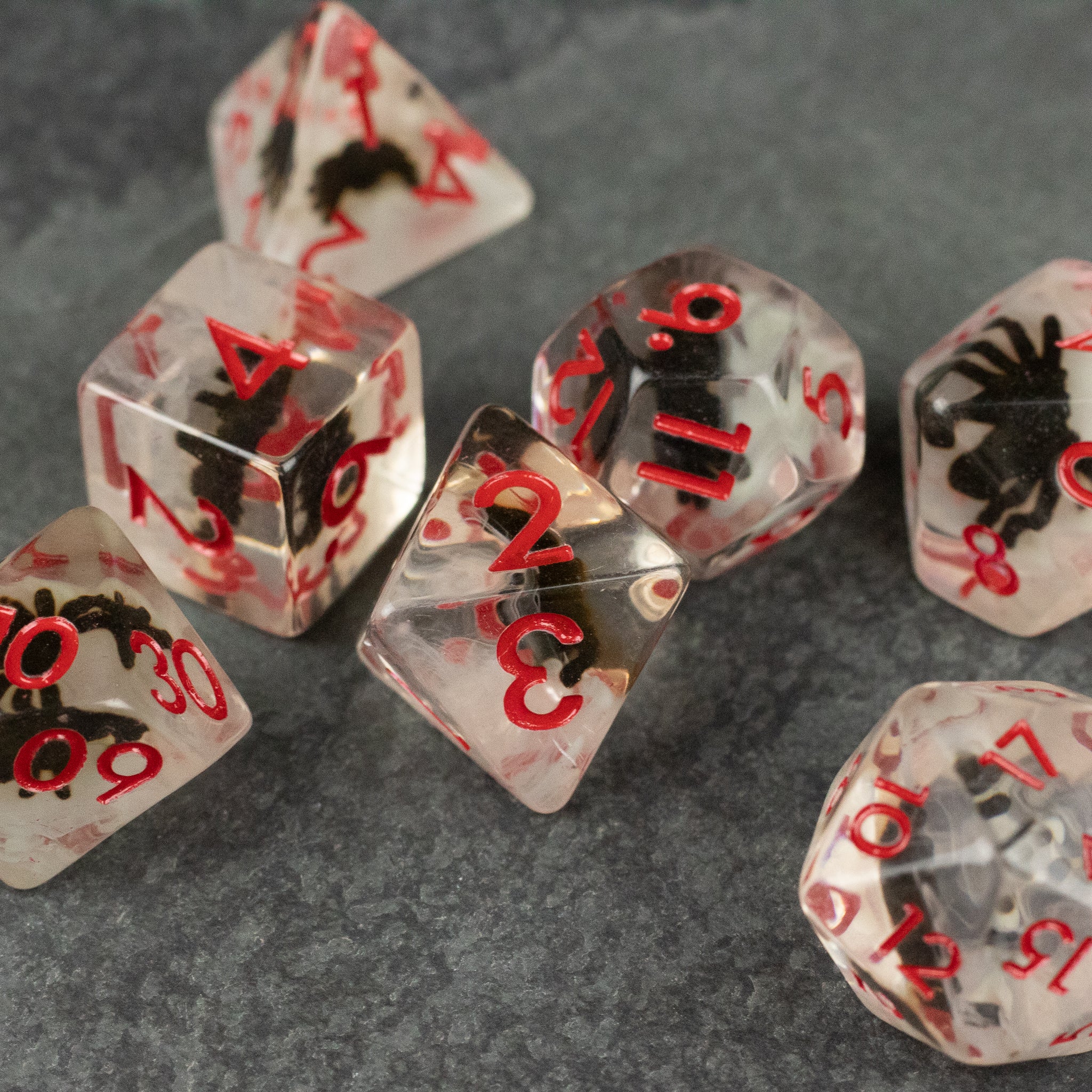 Black Spider Dice Set - White - Clear dice set with black spider inclusions and red numbers on each face.