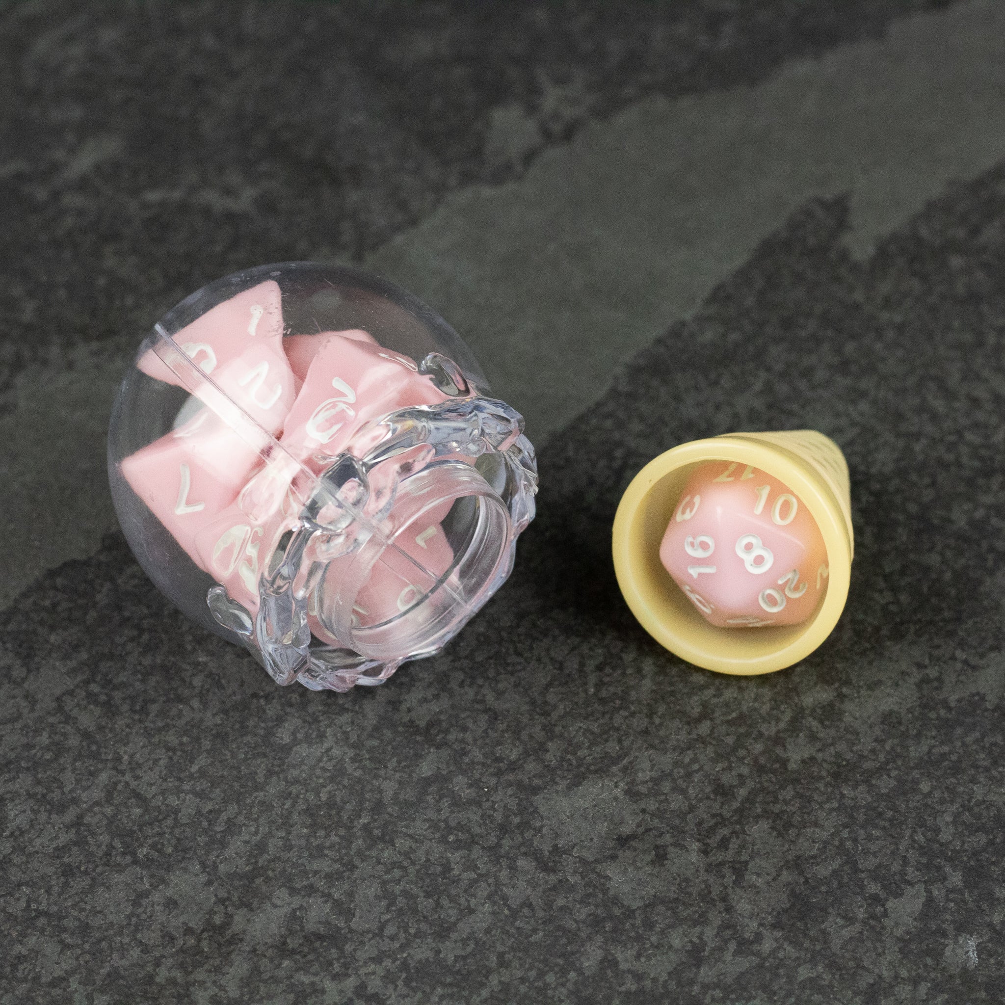 Dice Cream Cones - Pink 20-sided dice shaped like ice cream scoops in clear and beige cone holders on dark textured surface.