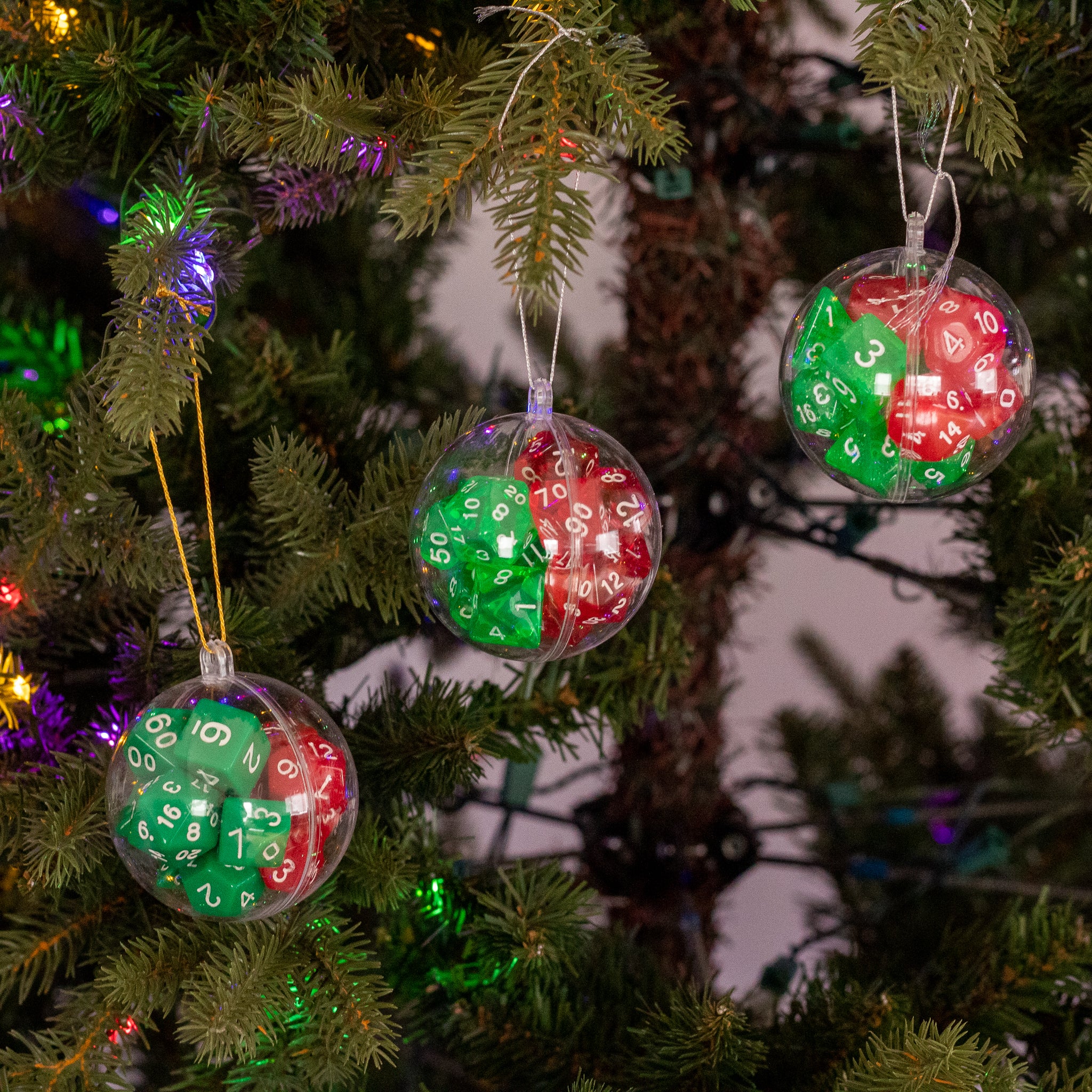 Christmas Dice Ball Ornaments - Clear round Christmas ornaments filled with red and green dice, hanging on a pine tree branch.