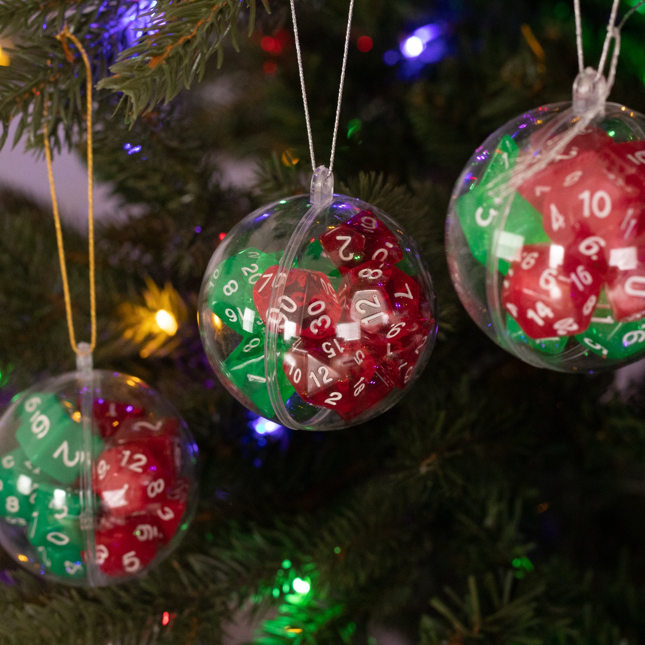 Christmas Dice Ball Ornaments - Clear plastic ball ornaments filled with red and green polyhedral dice hanging on a Christmas tree.