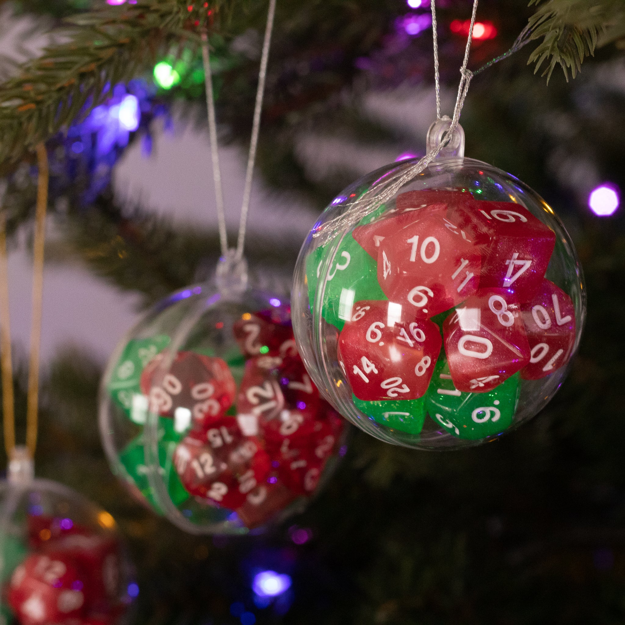 Christmas Dice Ball Ornaments - Clear spherical ornaments filled with red and green polyhedral dice hanging on a Christmas tree.