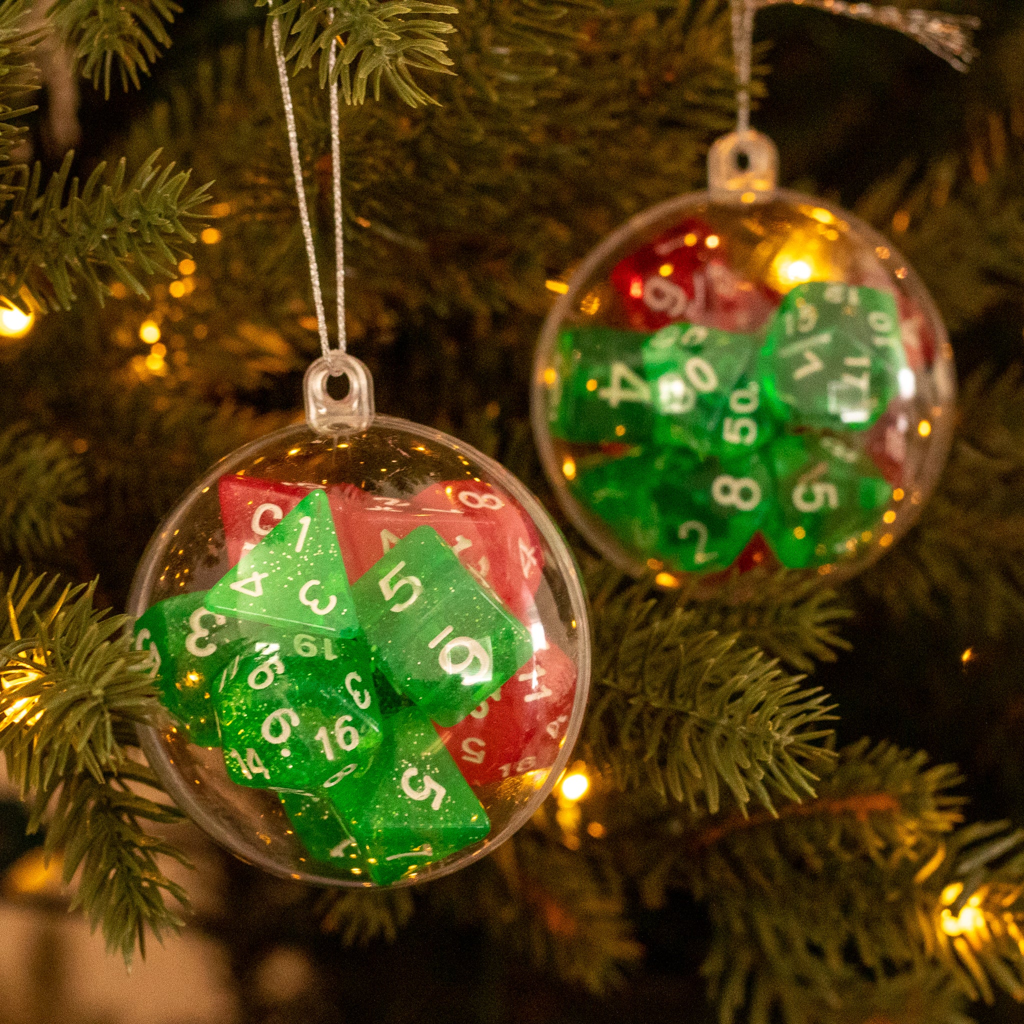 Christmas Dice Ball Ornaments - Clear ball ornaments filled with green and red polyhedral dice, hanging on a lit Christmas tree.