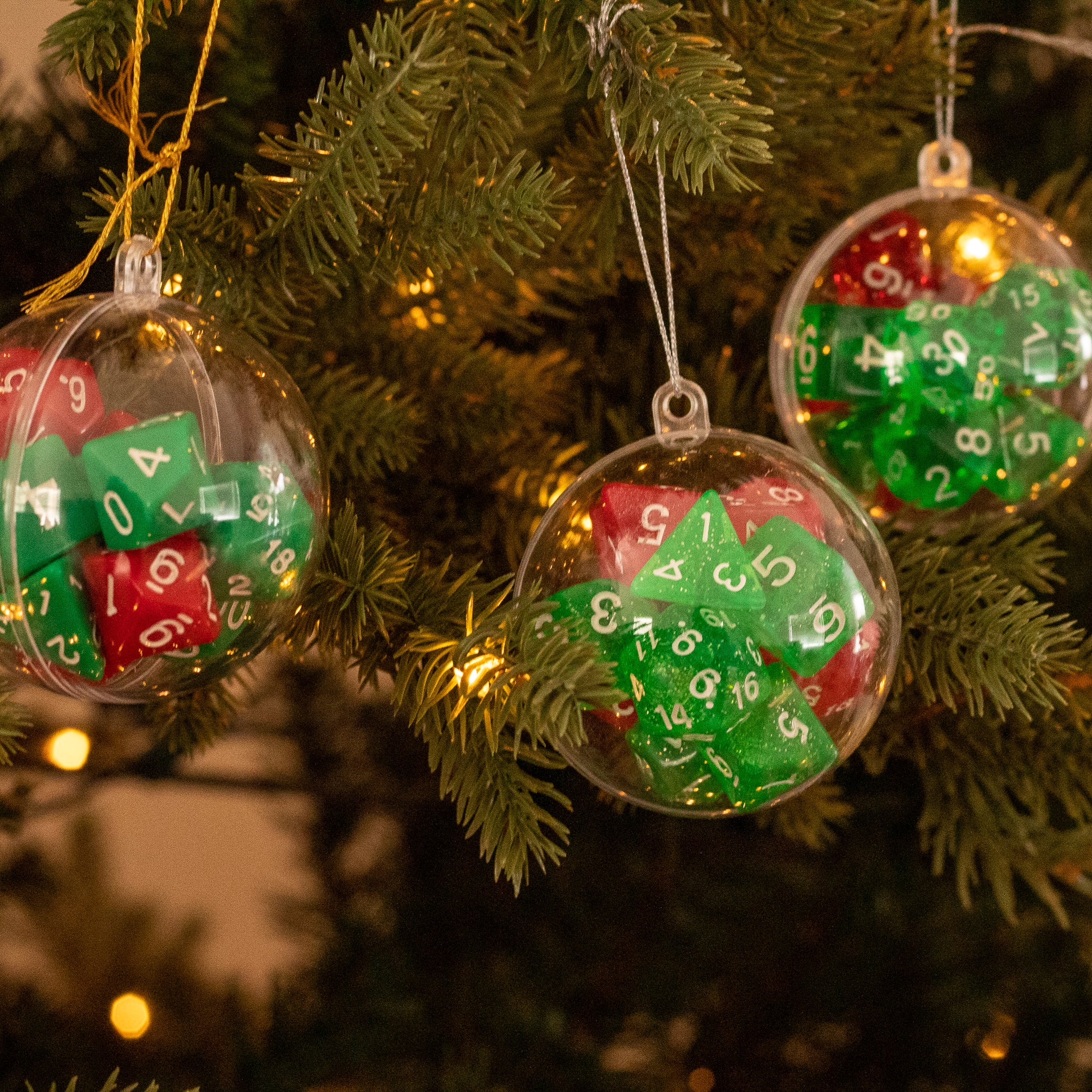 Christmas Dice Ball Ornaments - Clear Christmas ball ornaments filled with red and green dice hanging on a tree branch.