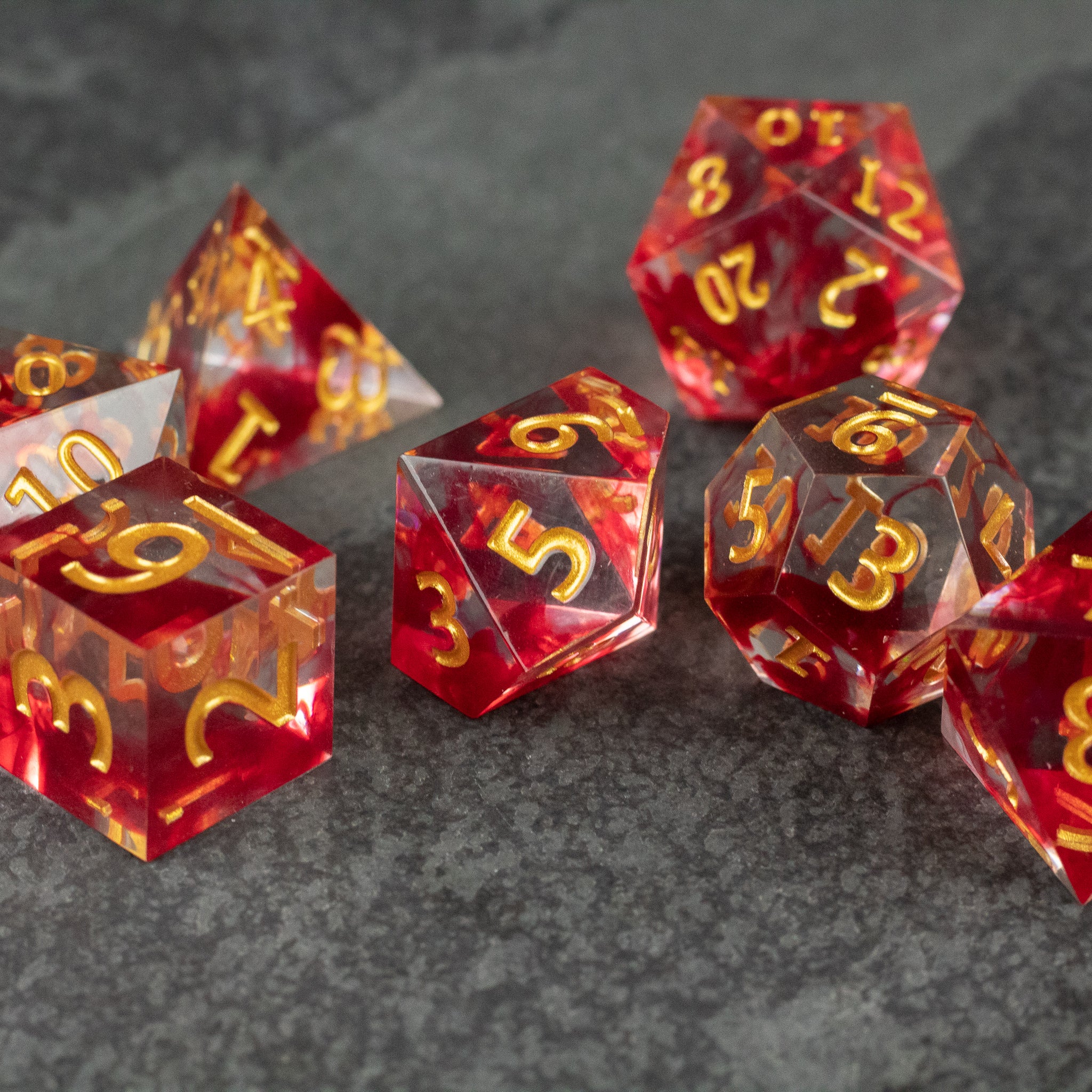 Blood Pact Dice Set - Translucent red and black sharp-edged polyhedral dice with gold numbering for tabletop games.