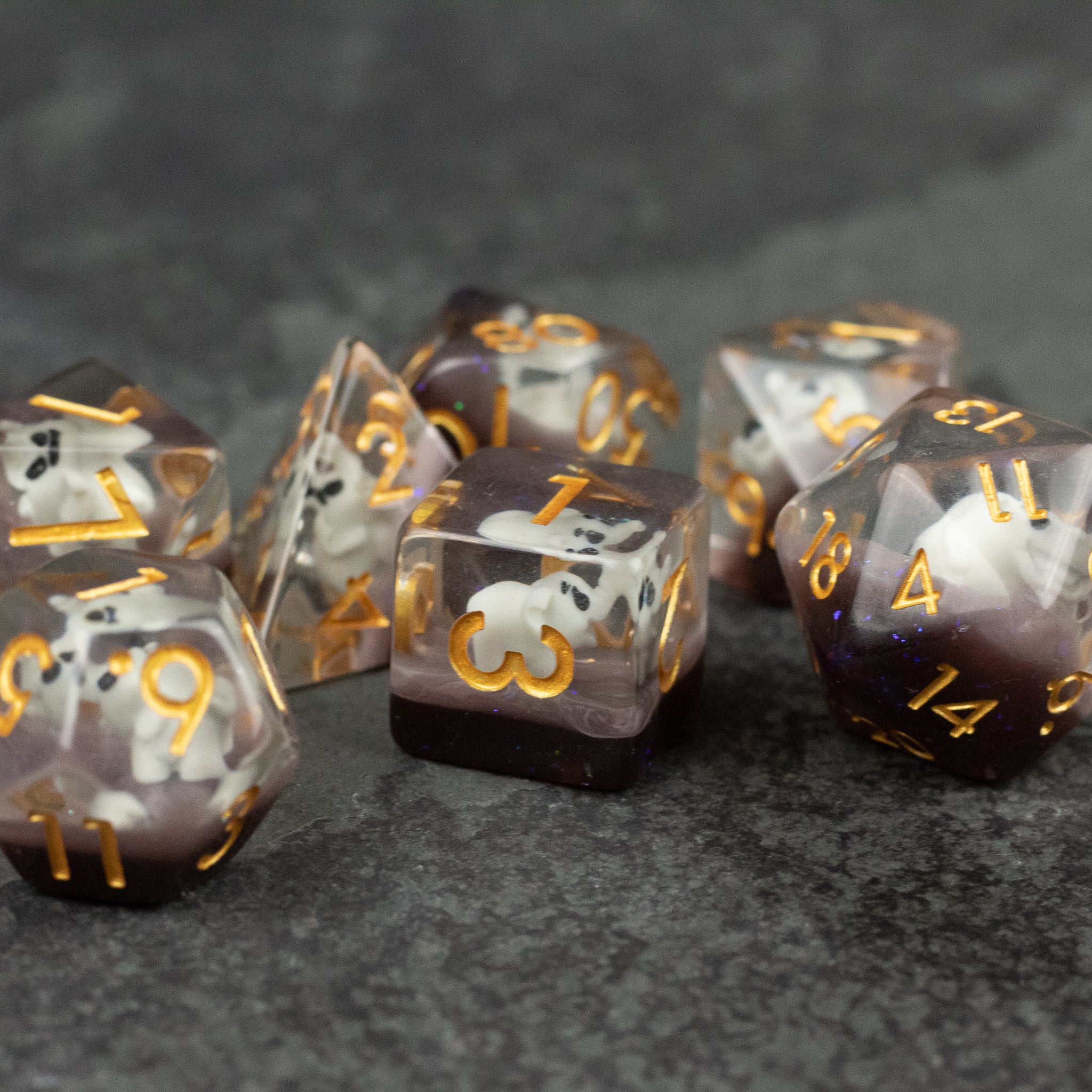 Elephant Dice Set - Set of translucent polyhedral dice with black, white, and purple elephant designs and gold numbers on a dark textured.