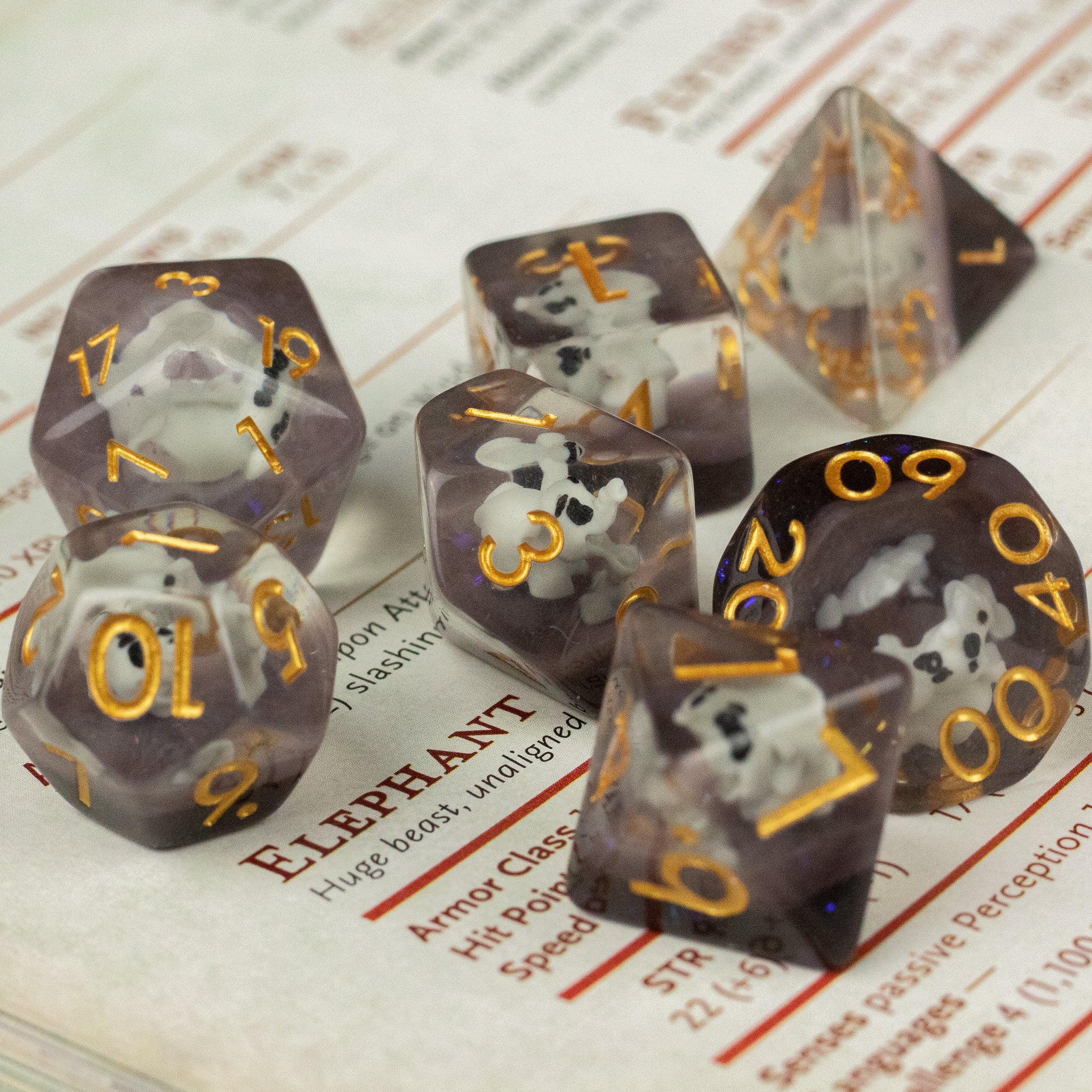 Elephant Dice Set - Translucent gray polyhedral dice set with white elephant inclusions and gold numbers, featuring seven dice shapes.