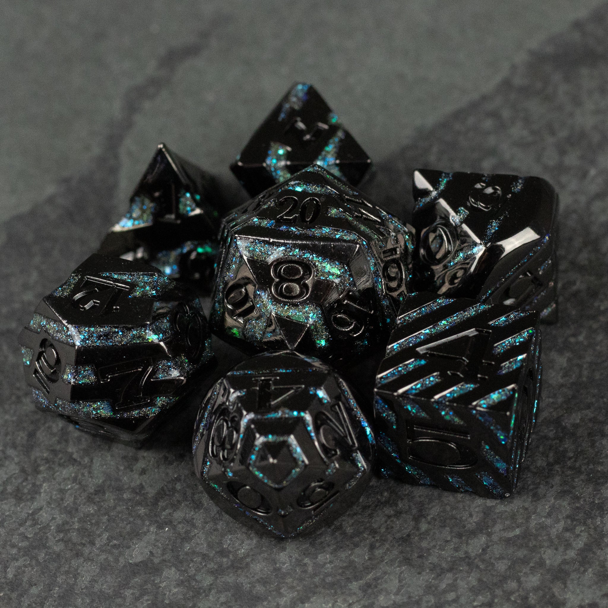 Blue Arcane Leyline Dice Set - Set of black metal polyhedral dice with glowing blue flecks and intricate arcane-style engravings.