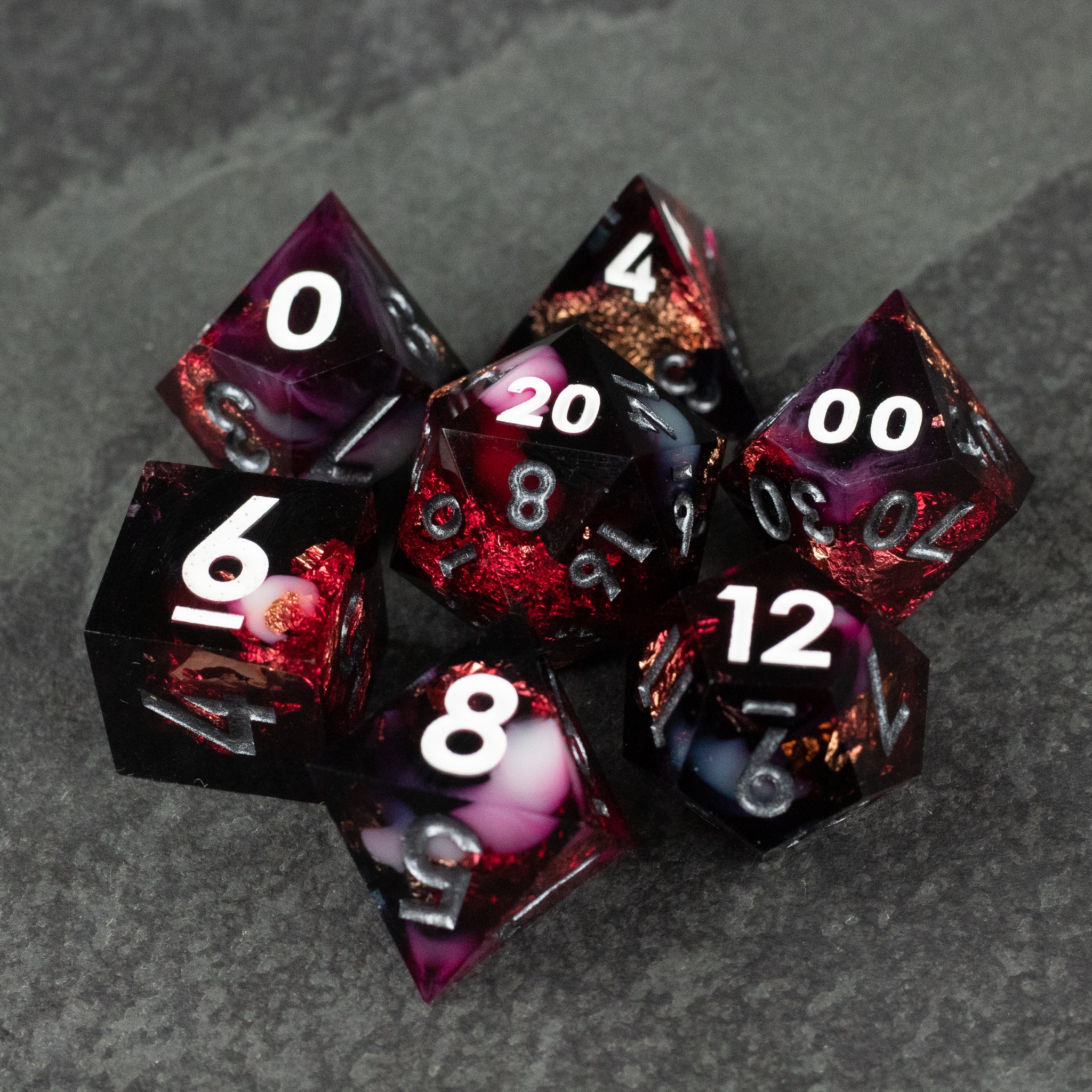 Sanguine Sacrament Dice Set - Seven sharp-edged polyhedral dice with deep red, black, and white swirling patterns and white numbering for tabletop gaming.