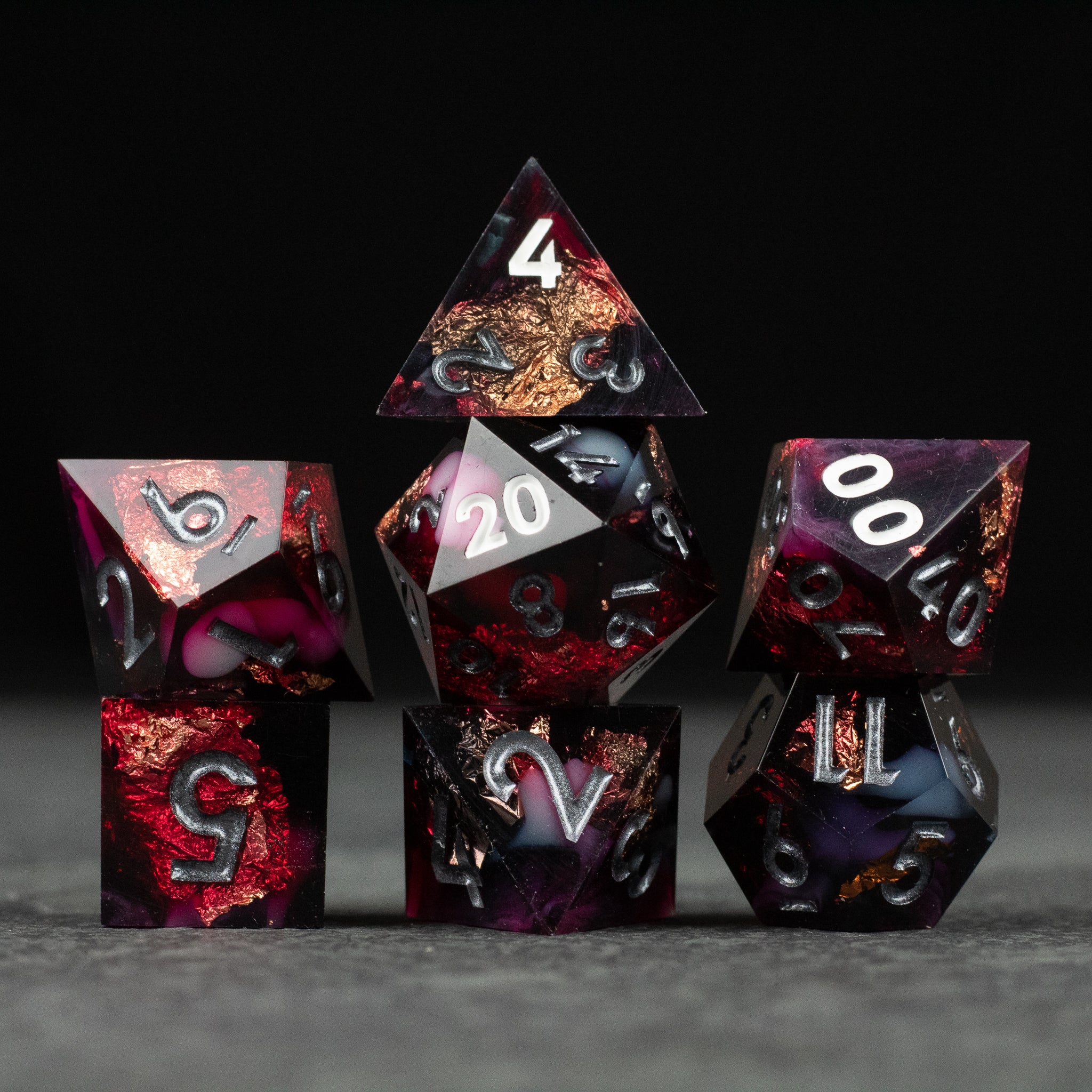 Sanguine Sacrament Dice Set - Set of seven sharp-edged polyhedral dice in deep red and black with white numbering and swirling patterns.