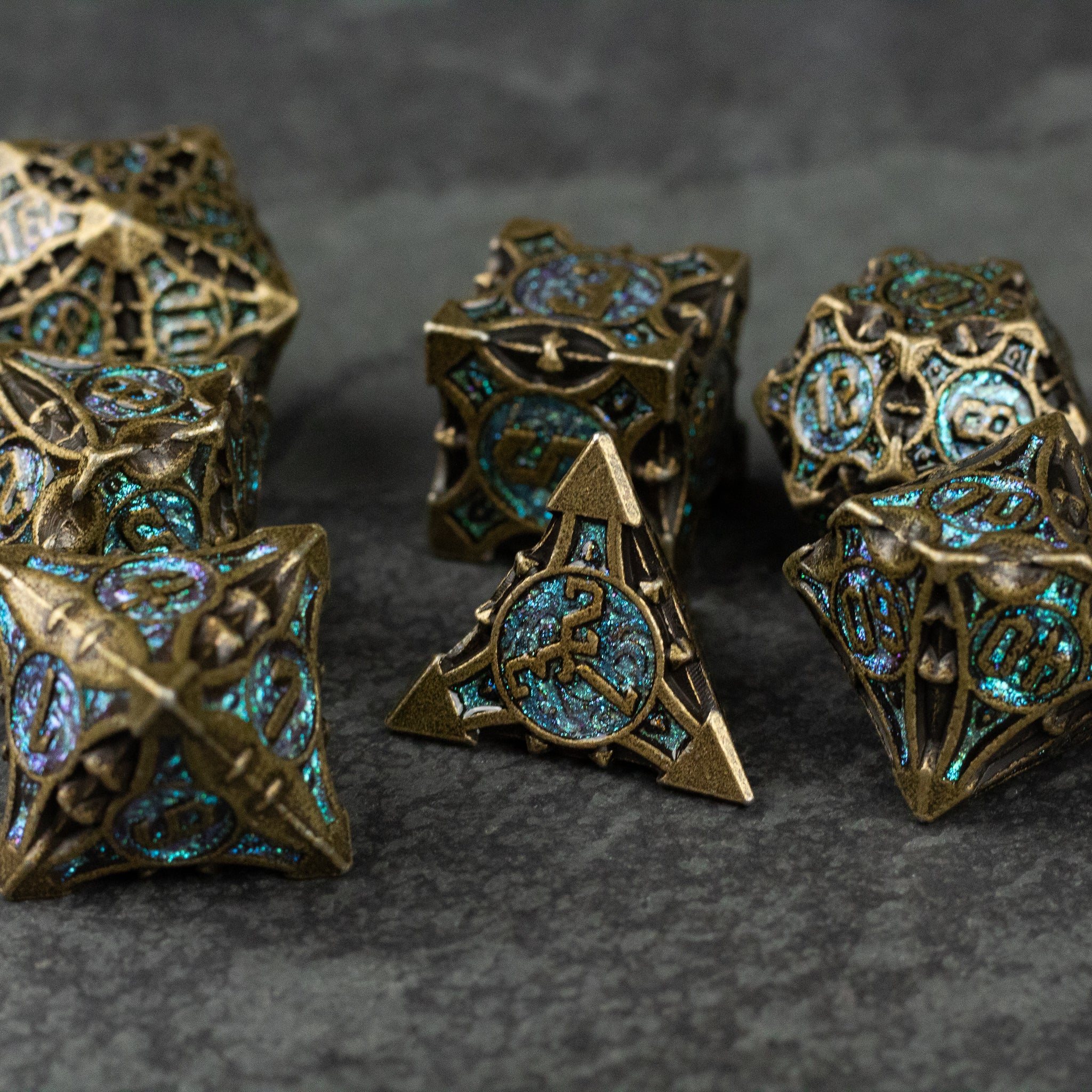 Empyrean Artifact Dice Set - Intricately designed metal dice set with antique bronze finish and blue glowing inlays, featuring multiple polyhedral shapes.