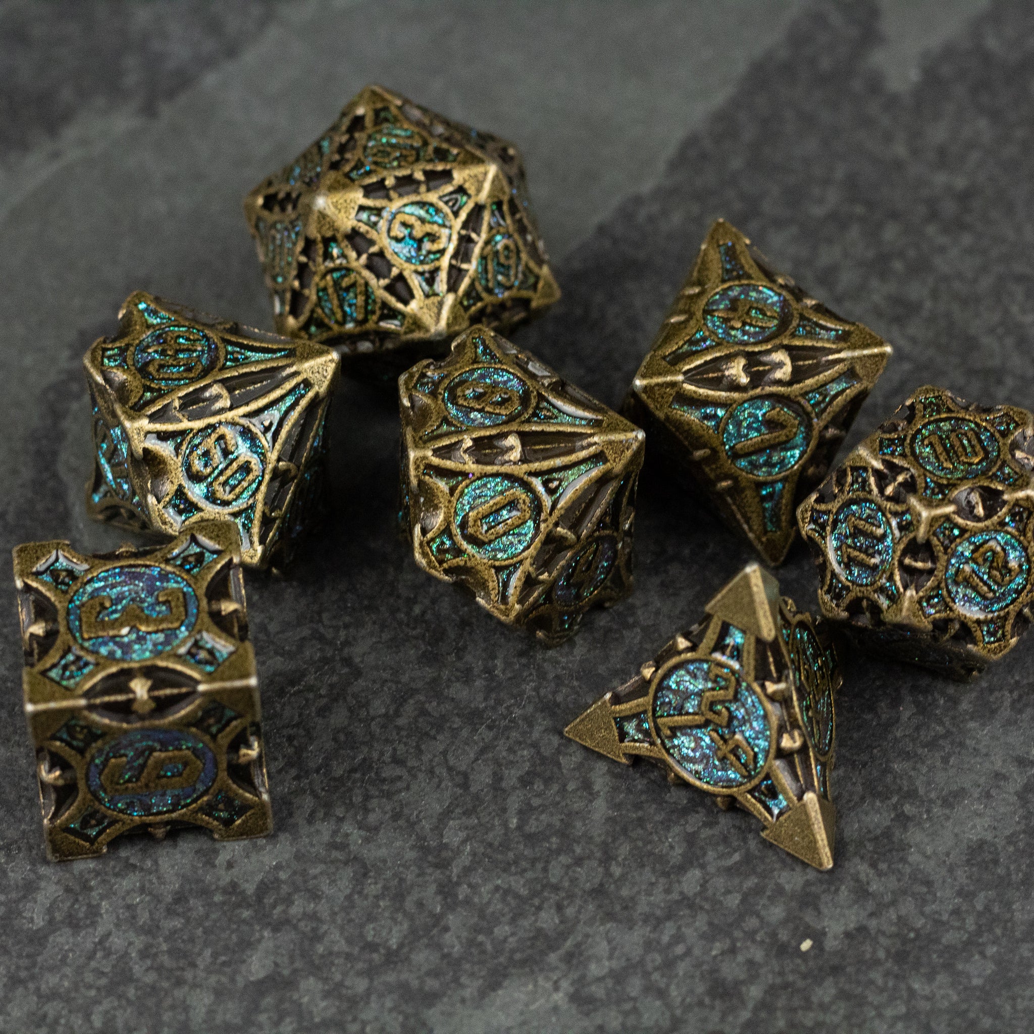 Empyrean Artifact Dice Set - Antique gold metal dice set with intricate blue-green filigree and rune-like designs.