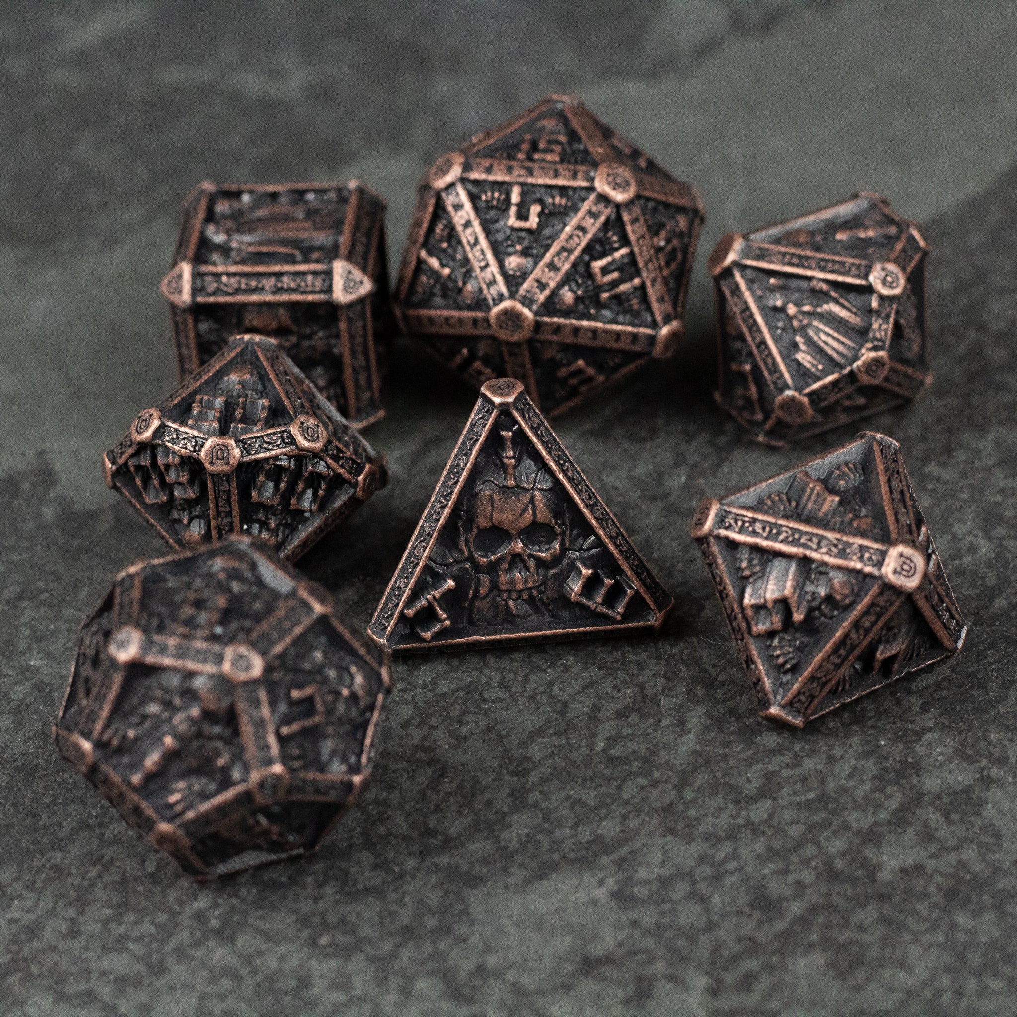 Bronze Necromancer Metal Dice Set - Bronze metal dice set with engraved skulls and necromancer-themed designs on dark background.
