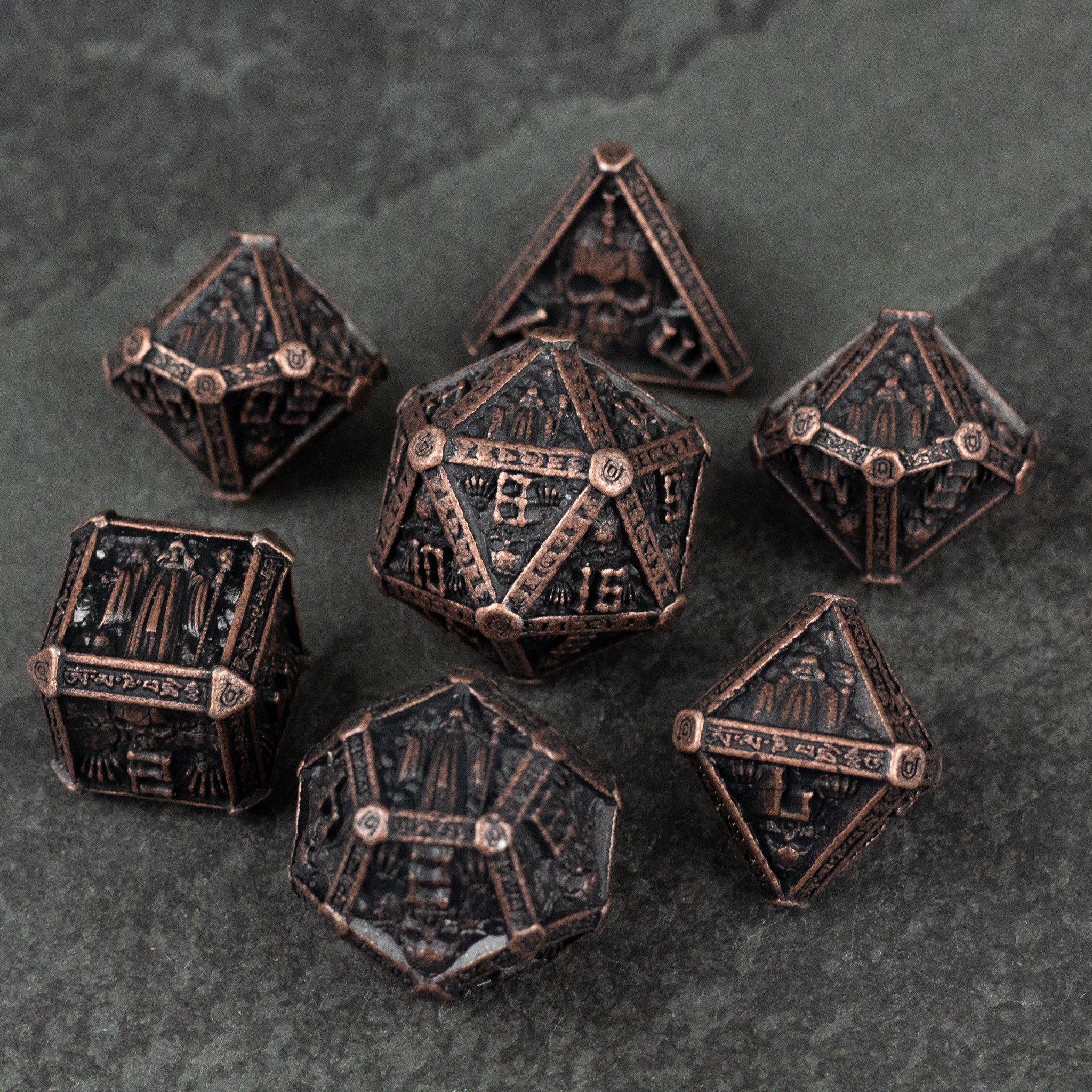 Bronze Necromancer Metal Dice Set - Bronze metal dice set with necromancer-themed engravings including skulls and bones, seven pieces.