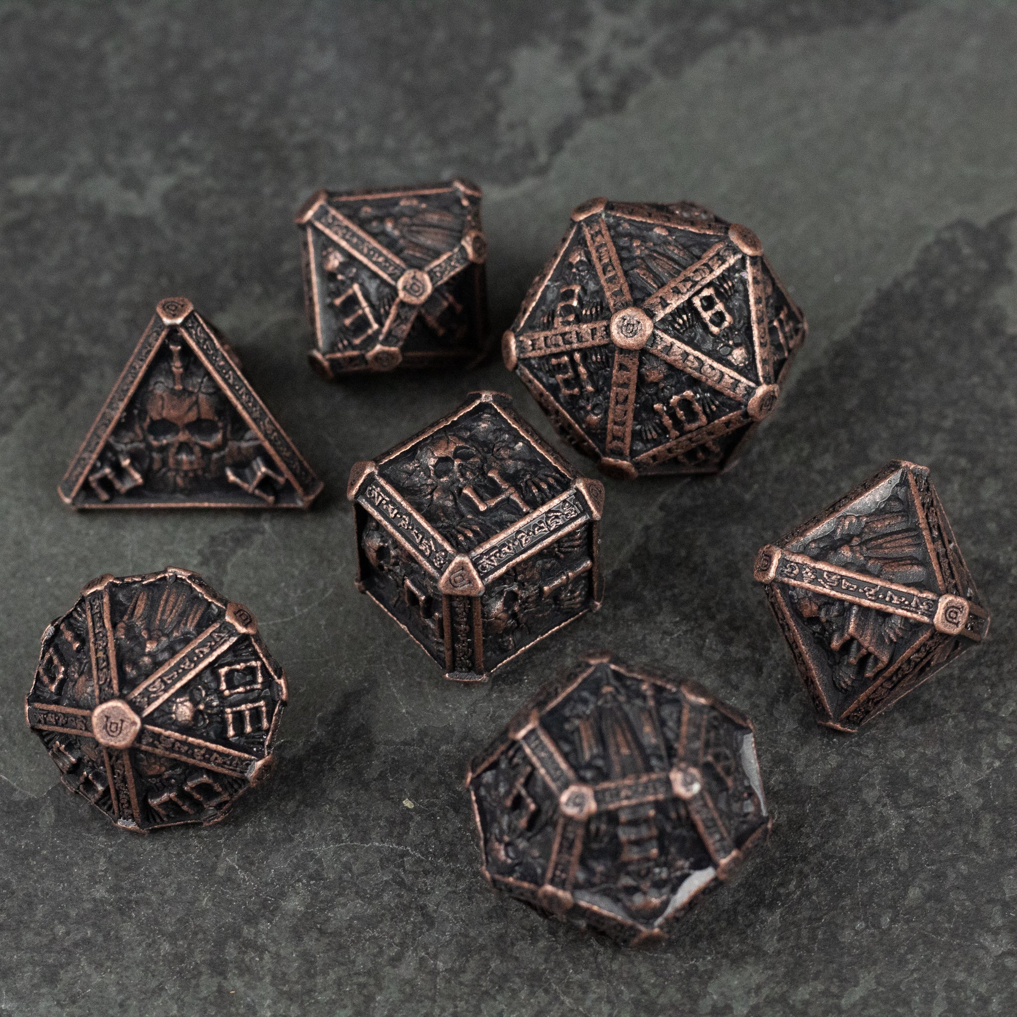Bronze Necromancer Metal Dice Set - Set of seven bronze-colored metal dice with intricate necromancer-themed engravings and aged finish.