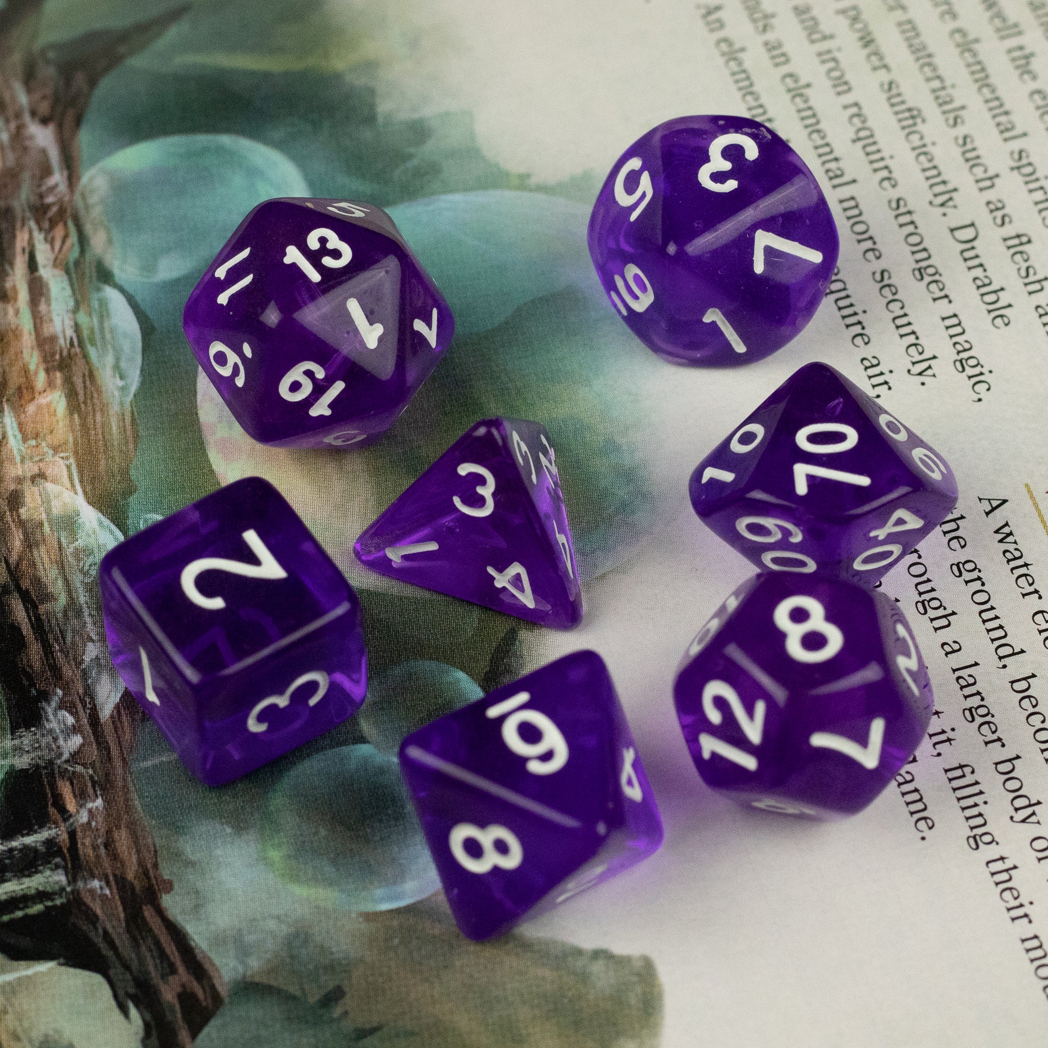 Purple Transparent Dice Set - Set of seven purple transparent polyhedral dice with white numbers on a book background.