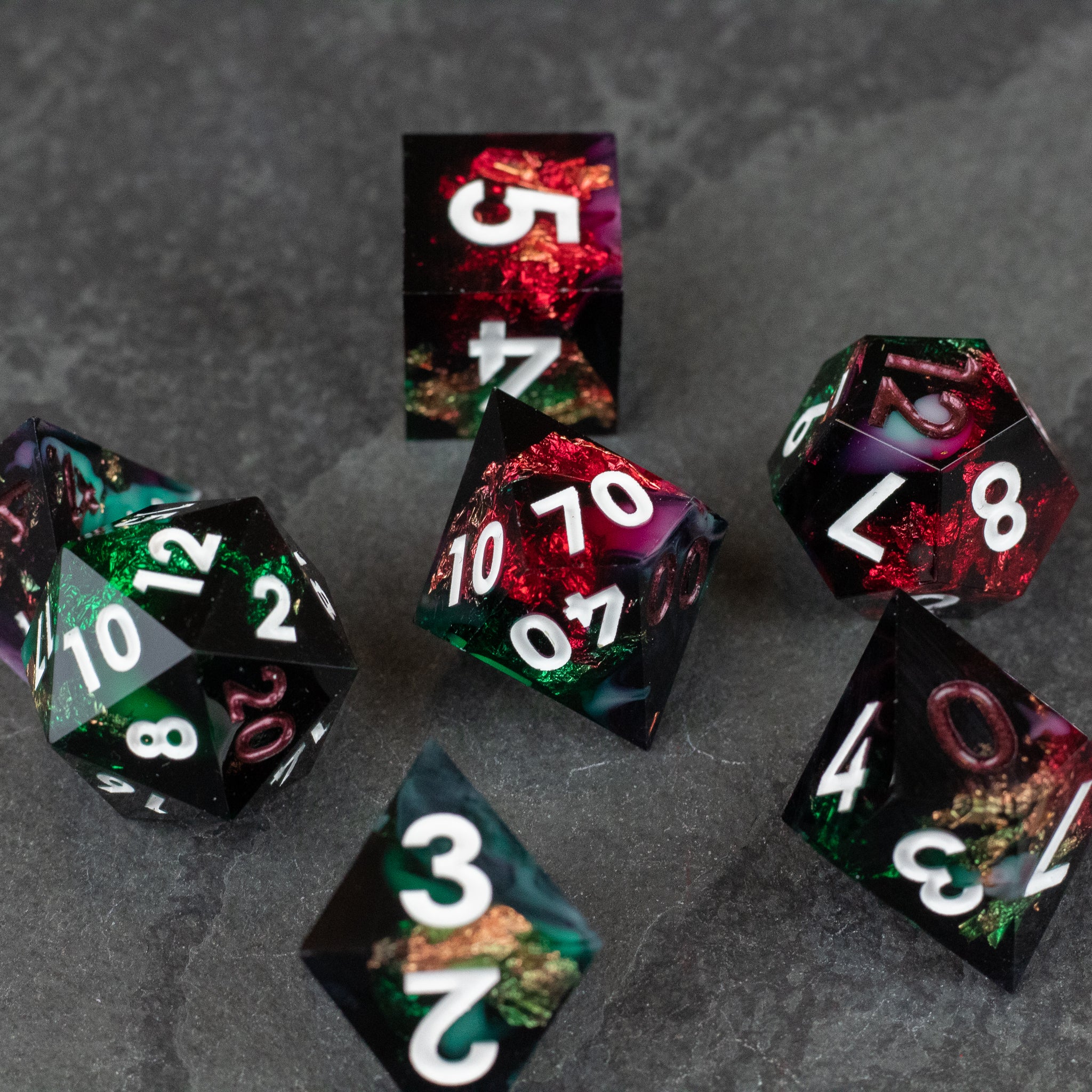 Chromatic Aberration Dice Set - Multi-colored sharp-edge polyhedral dice set with white numbers, featuring red, green, and black marbled patterns on gray.