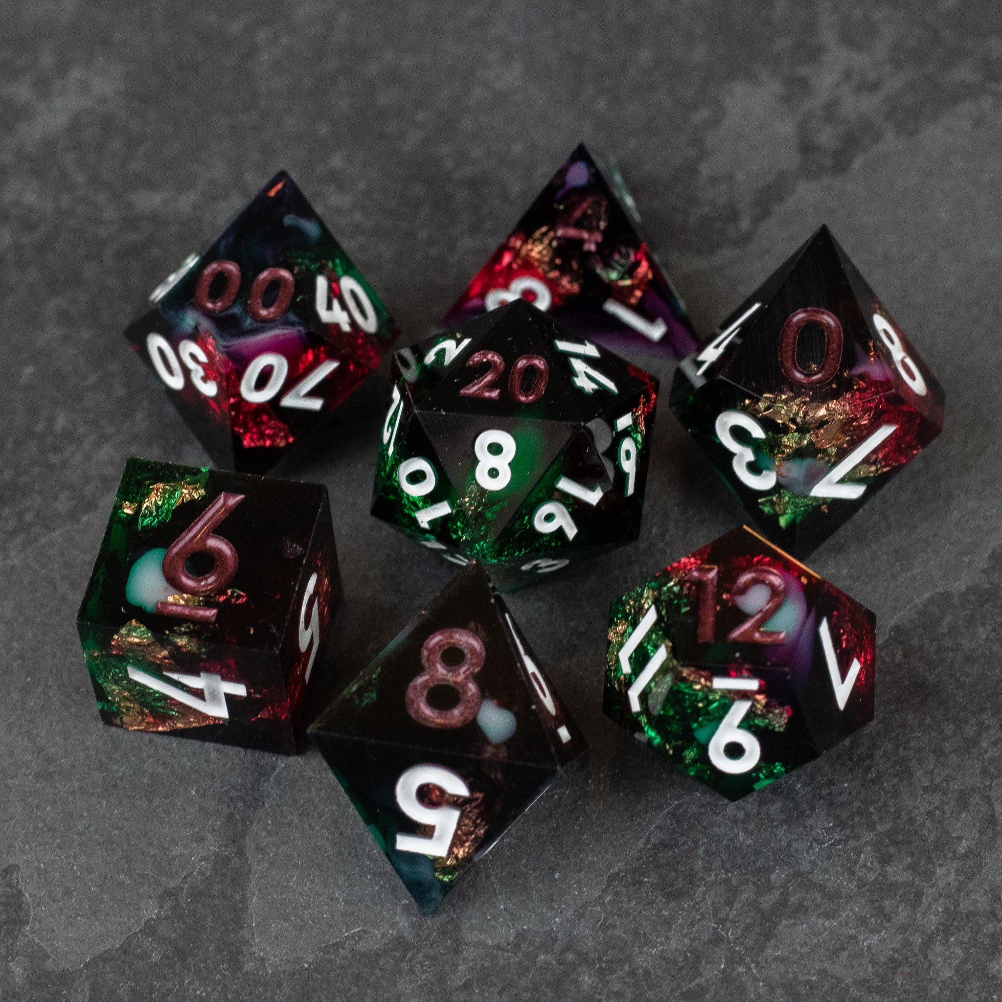 Chromatic Aberration Dice Set - Seven sharp-edged polyhedral dice in translucent chromatic colors with white numbering on a dark gray surface.