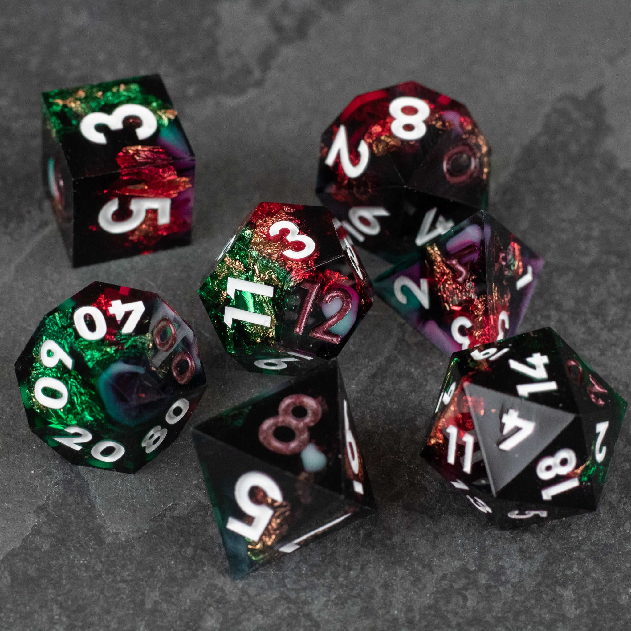 Chromatic Aberration Dice Set - Set of seven sharp-edged polyhedral dice with translucent red, green, and black colors and white numbers.