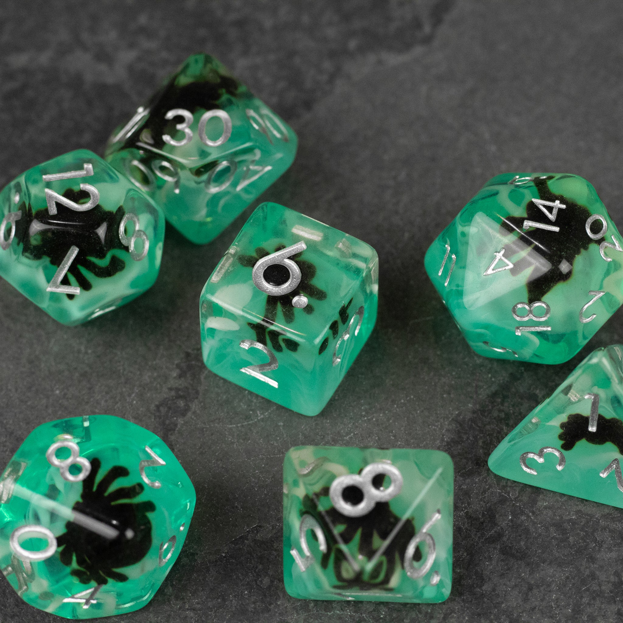 Black Spider Dice Set - Green - Green translucent polyhedral dice set with black spider designs and white numbering on a dark surface.