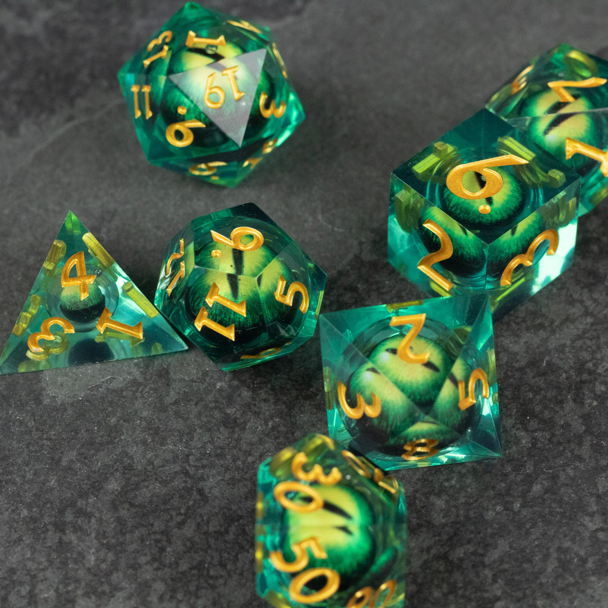 Green Beholder's Eye Dice Set - Seven green translucent polyhedral dice with swirling liquid core and sharp edges, gold numbers visible on each face.
