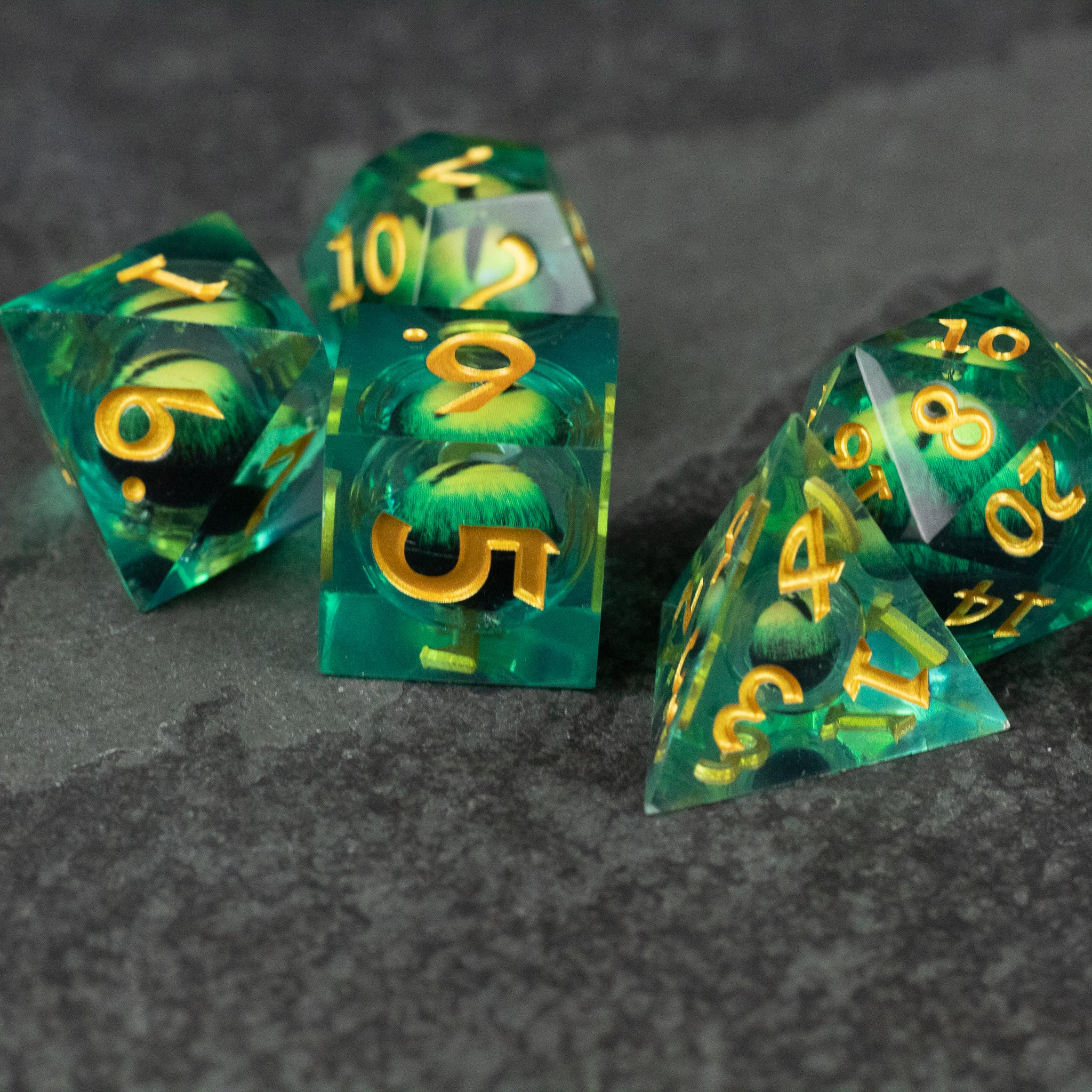 Green Beholder's Eye Dice Set - Translucent green polyhedral dice set with gold numbers, featuring sharp edges and a liquid core effect.