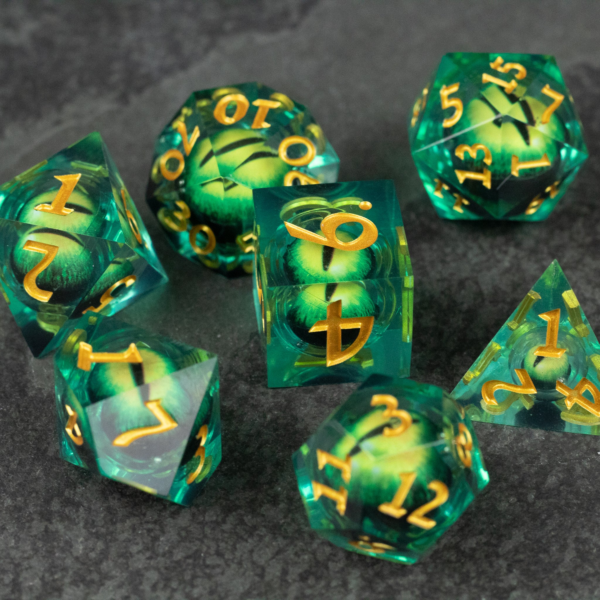 Green Beholder's Eye Dice Set - Set of translucent green polyhedral dice with swirling liquid core and sharp gold numbers.