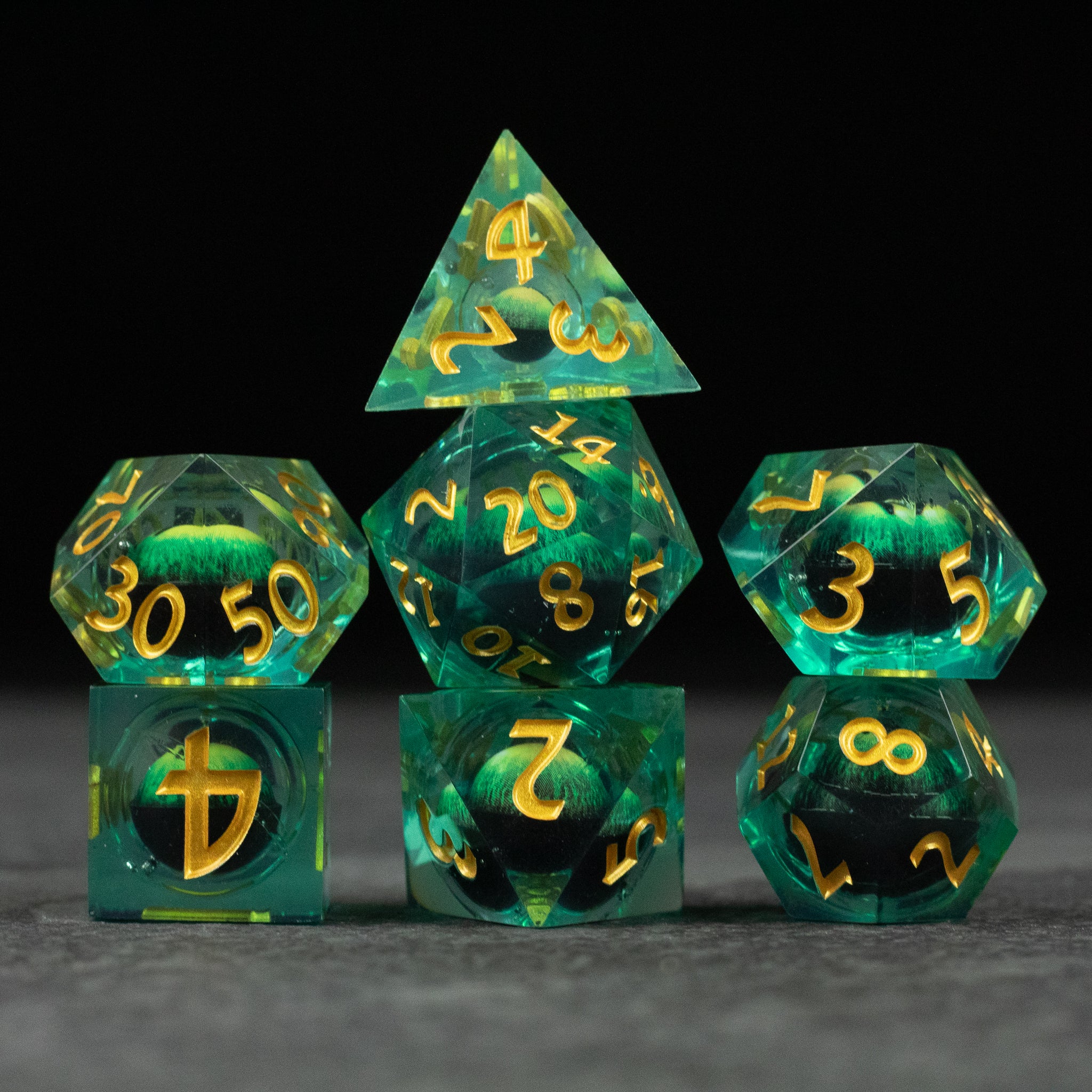 Green Beholder's Eye Dice Set - Green polyhedral dice set with gold numbers, sharp edges, and swirling liquid core design.
