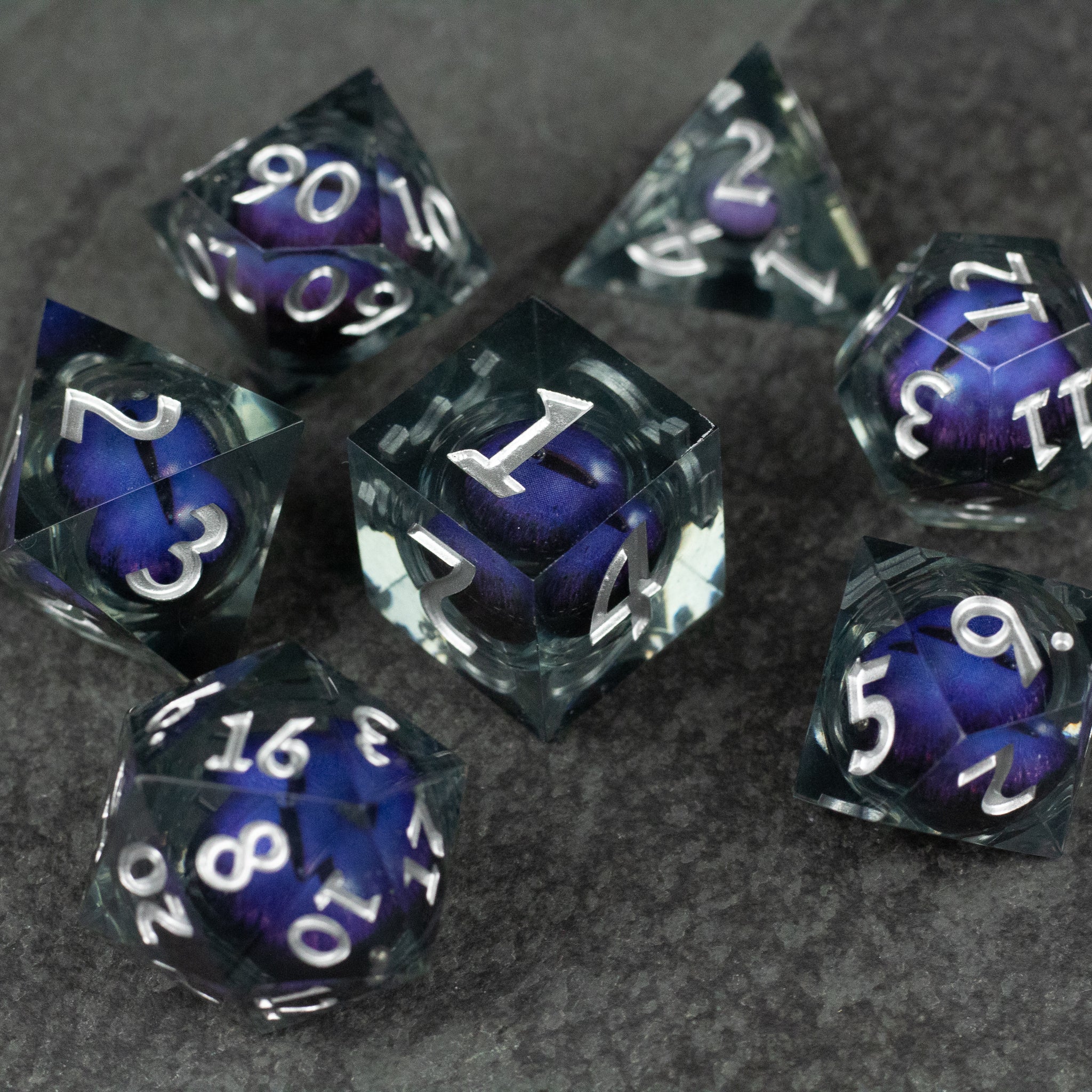 Purple Beholder's Eye Dice Set - Set of seven sharp-edged dice with purple liquid core and white numbers on transparent black outer shell.