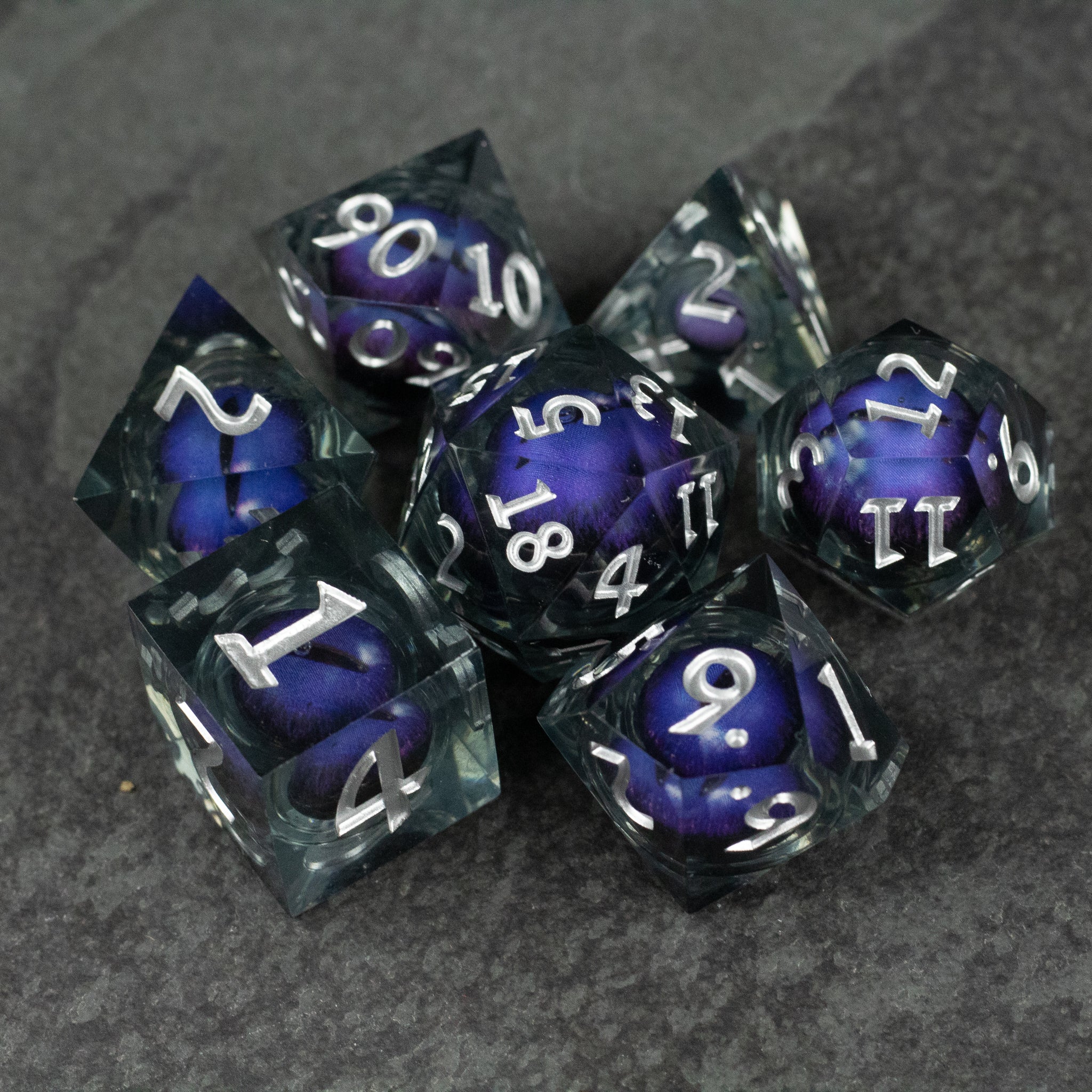 Purple Beholder's Eye Dice Set - Set of seven sharp-edged dice with translucent black and purple liquid core and white numbering.