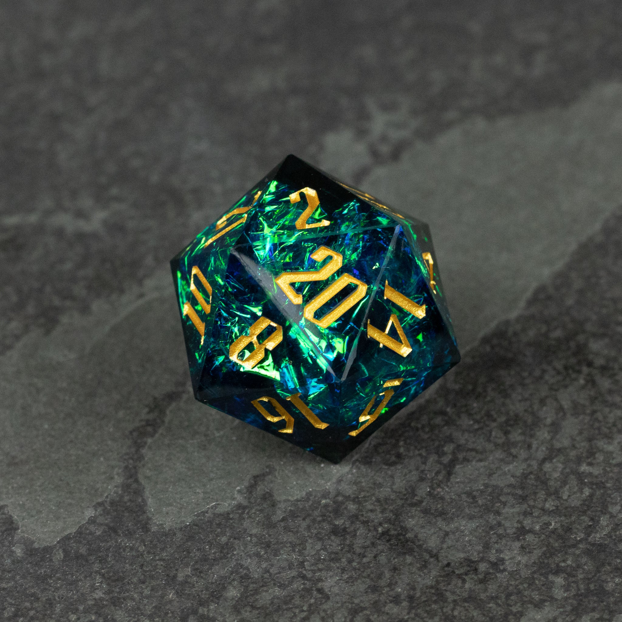 33mm Blue Shimmer D20 - 33mm blue shimmer d20 dice with gold numbers on a dark textured surface.