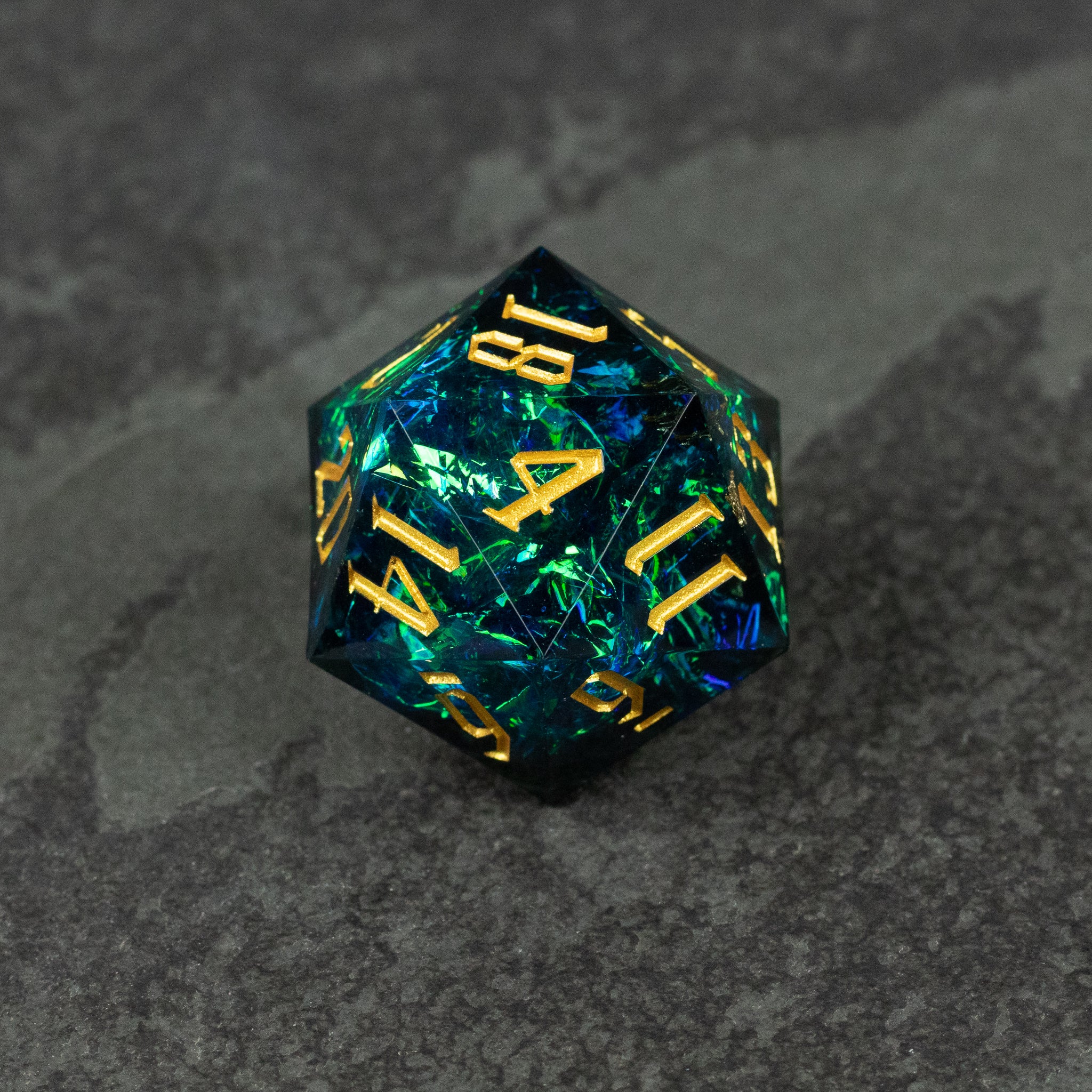 33mm Blue Shimmer D20 - Blue translucent 33mm d20 die with gold shimmer and gold numbers on dark gray surface.