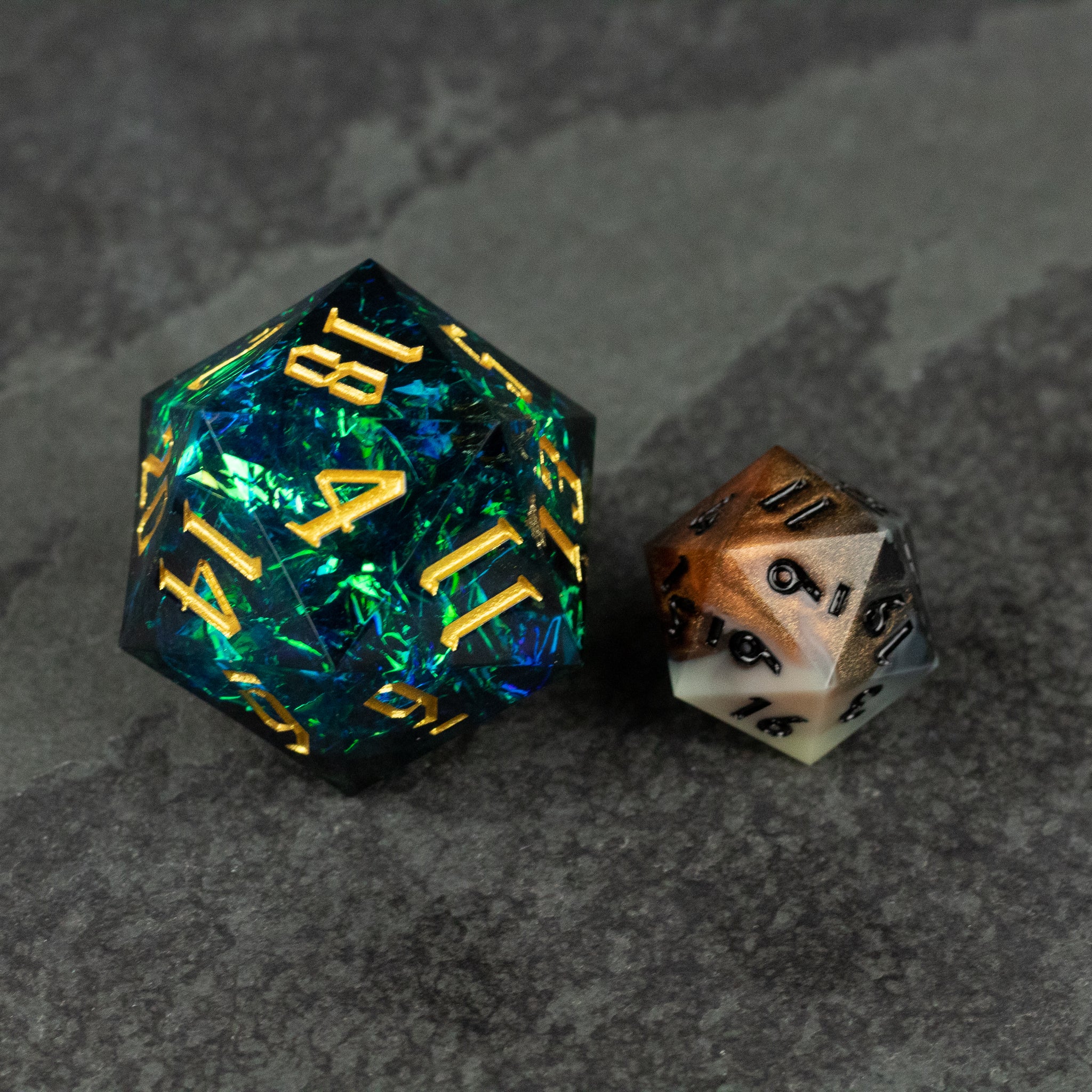 33mm Blue Shimmer D20 - Large 33mm translucent blue d20 die with gold numbers beside smaller black-and-white d20 die on gray surface.