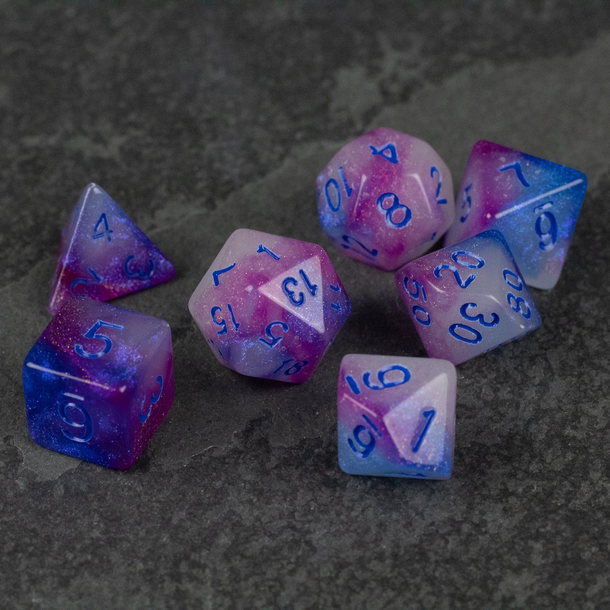 Emberlight Twilight Glow-in-the-Dark Dice Set - Set of seven polyhedral dice with a gradient of purple, pink, and blue, featuring glow-in-the-dark material and bright blue.