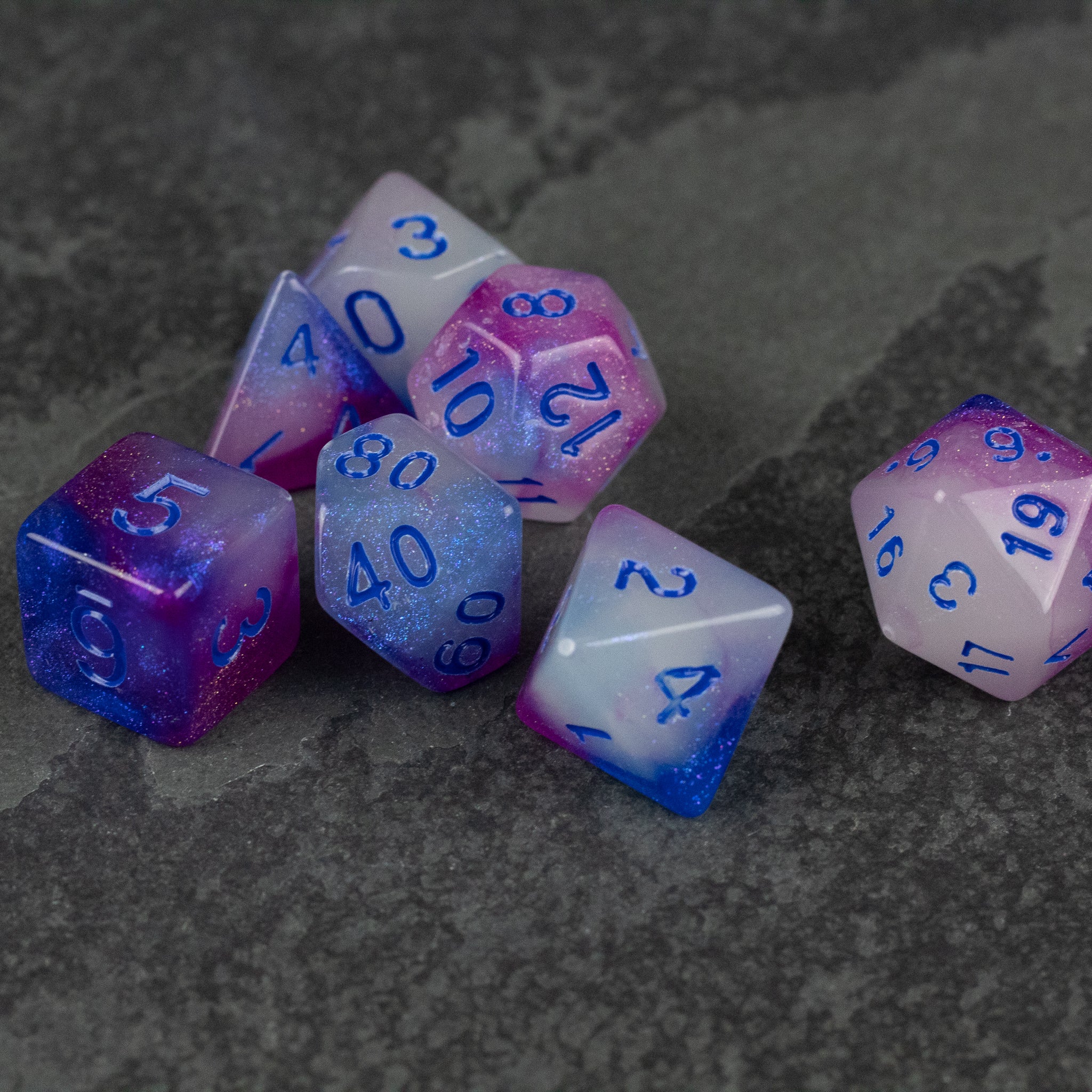Emberlight Twilight Glow-in-the-Dark Dice Set - Set of seven polyhedral dice with purple and blue gradient, translucent with glowing white numbers.