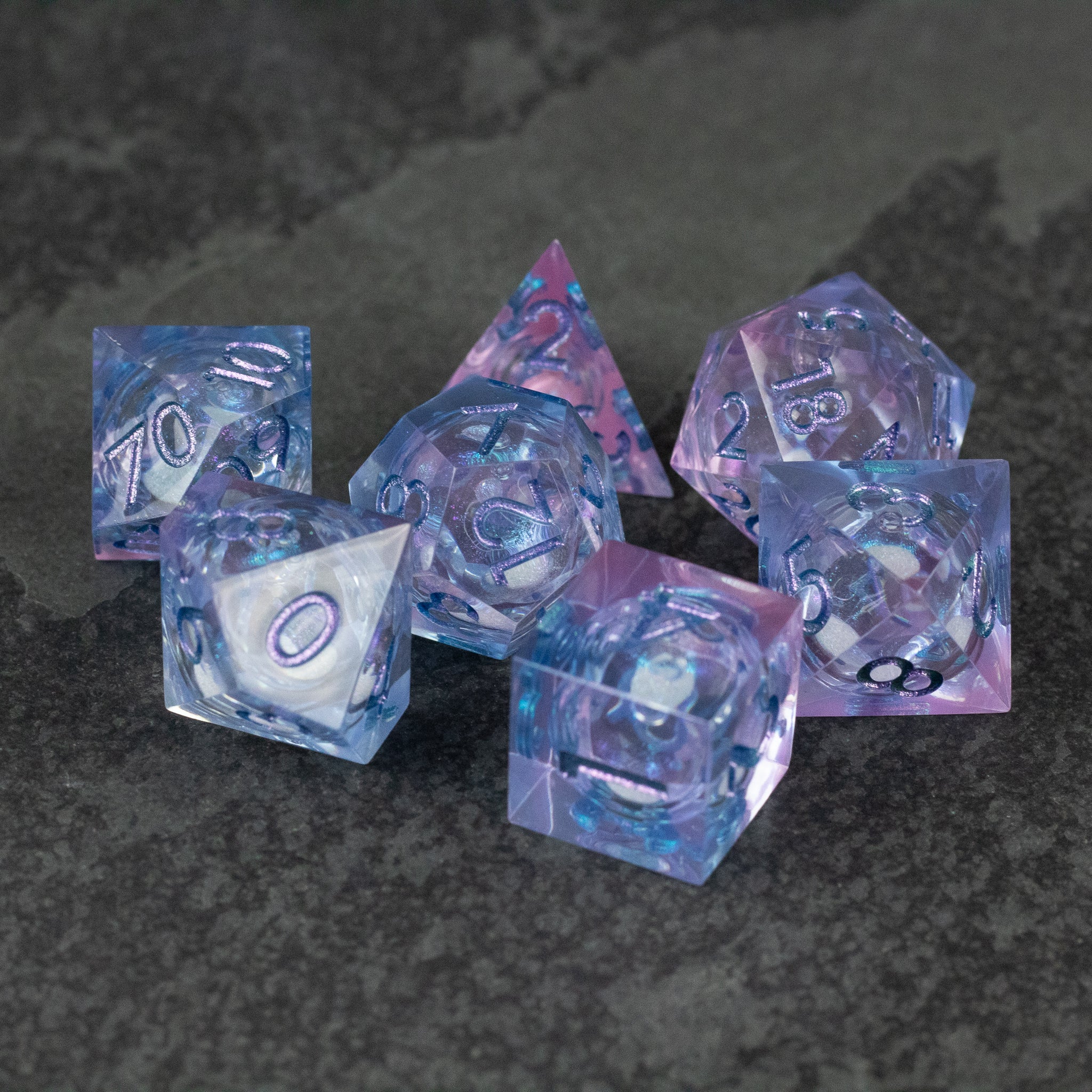 Fae Magic - Liquid Core Dice Set - Six-piece translucent polyhedral dice set in purple and blue swirls with black numbers.