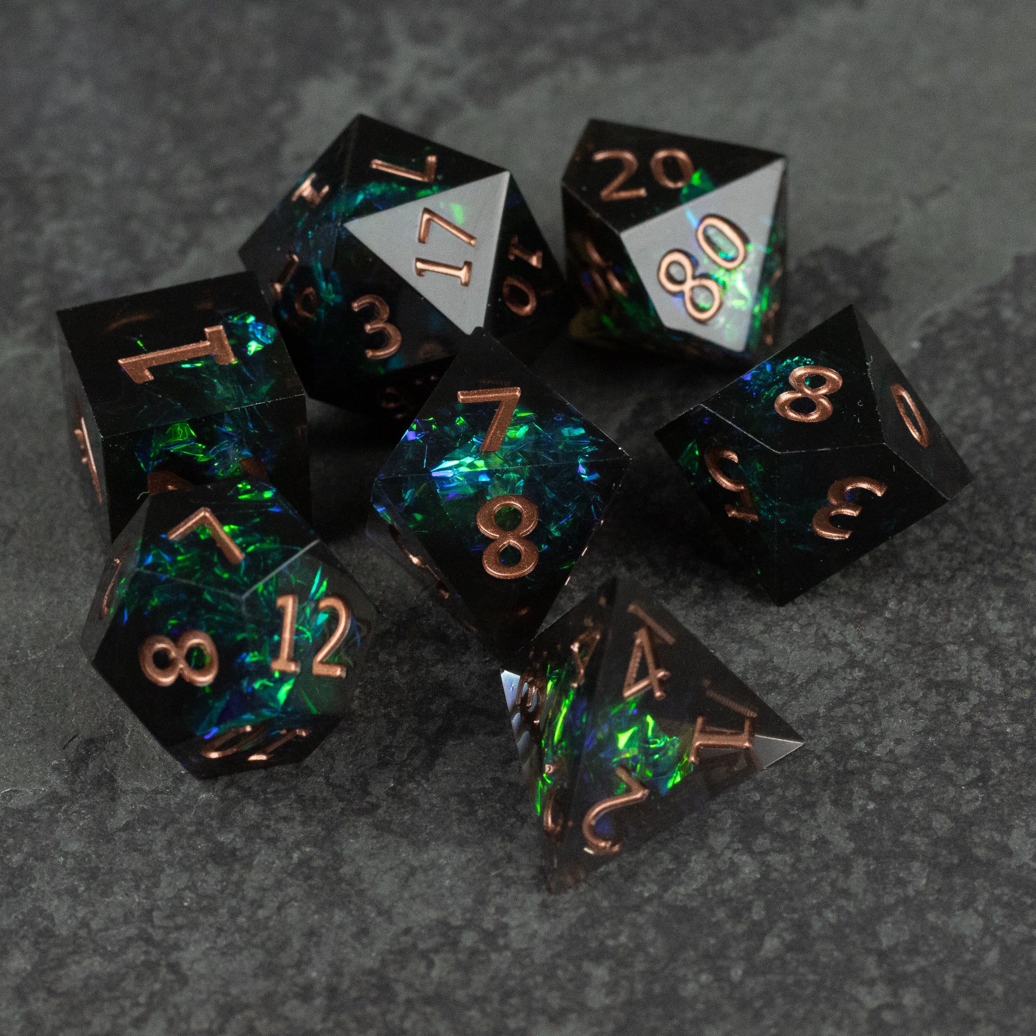 The Underdark Dice Set - Seven multifaceted polyhedral dice with sharp edges, featuring a smoky translucent black base with glowing green and blue.