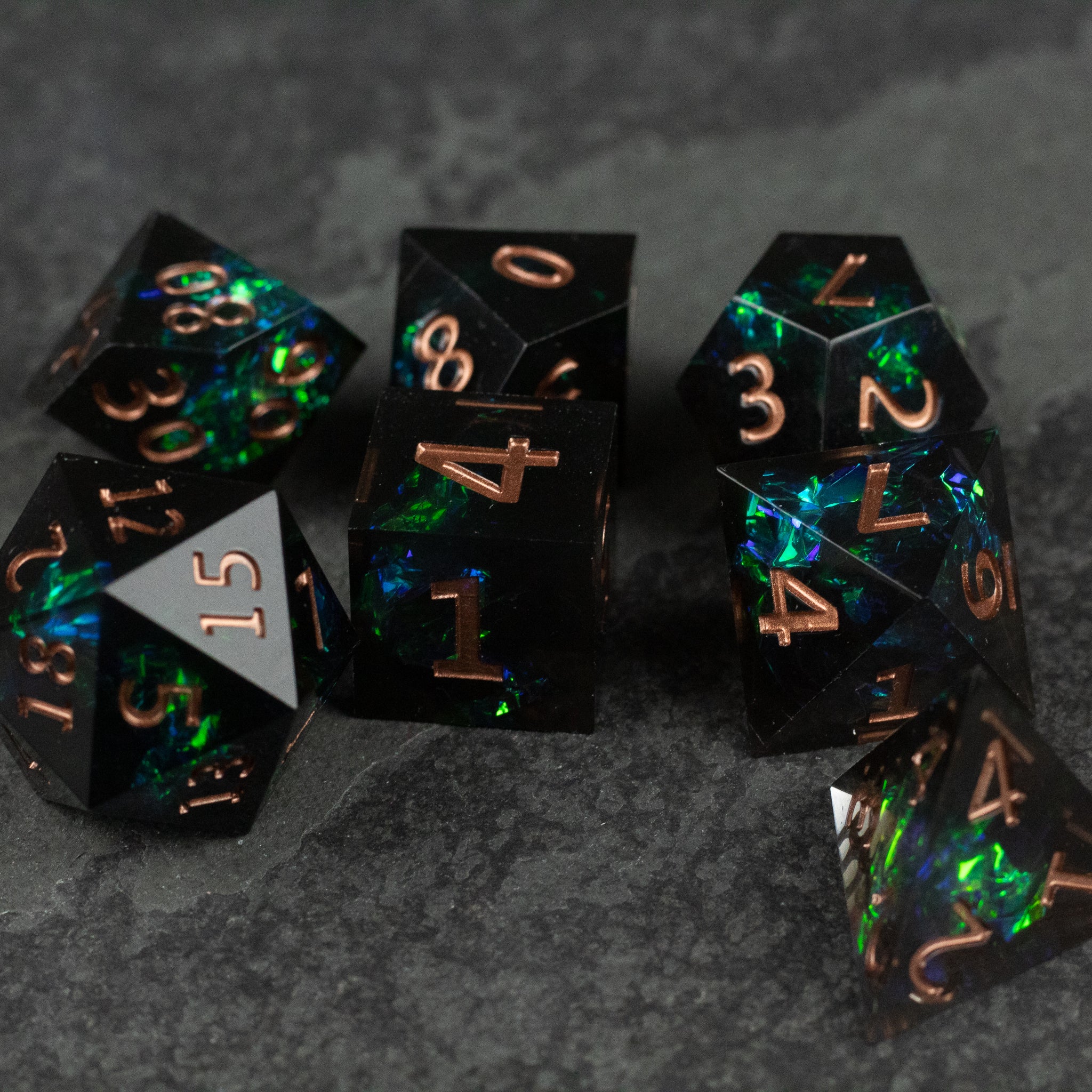 The Underdark Dice Set - Black polyhedral dice set with sharp edges, iridescent blue-green flecks, and copper numbers.