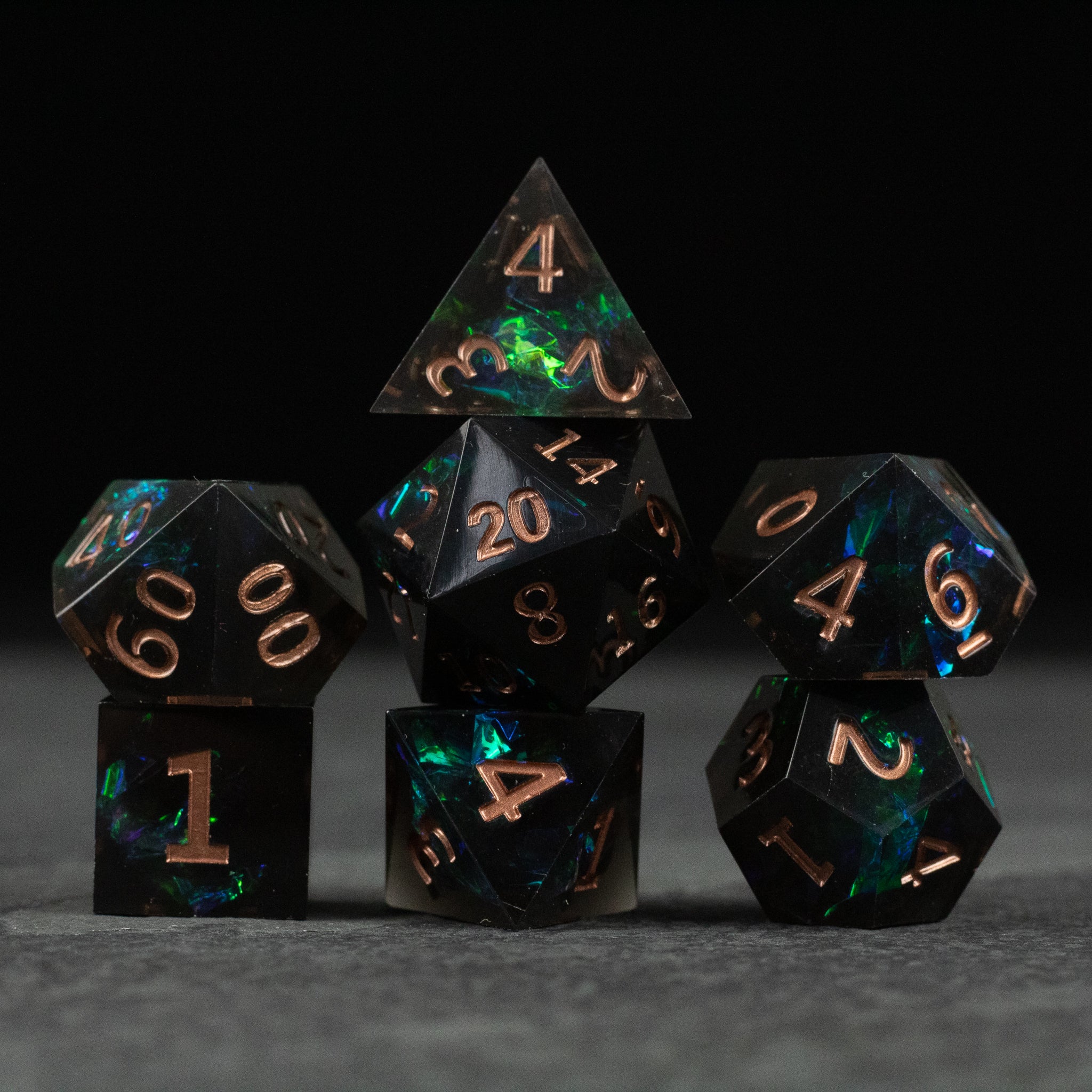 The Underdark Dice Set - Set of seven black polyhedral dice with iridescent green and blue swirls and sharp copper-colored numbers.