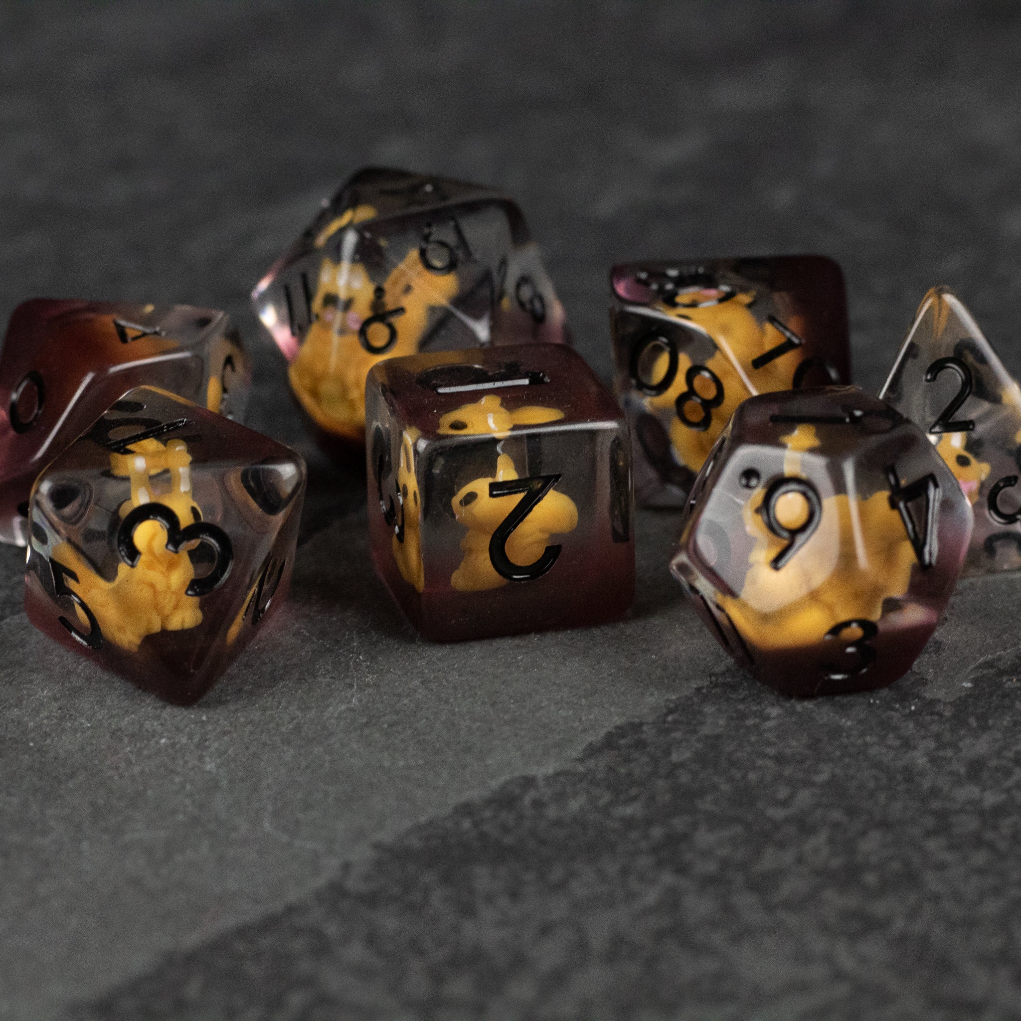 Squirrel Dice Set - Seven polyhedral dice with translucent dark brown and amber marbled design and black numbers on a gray surface.