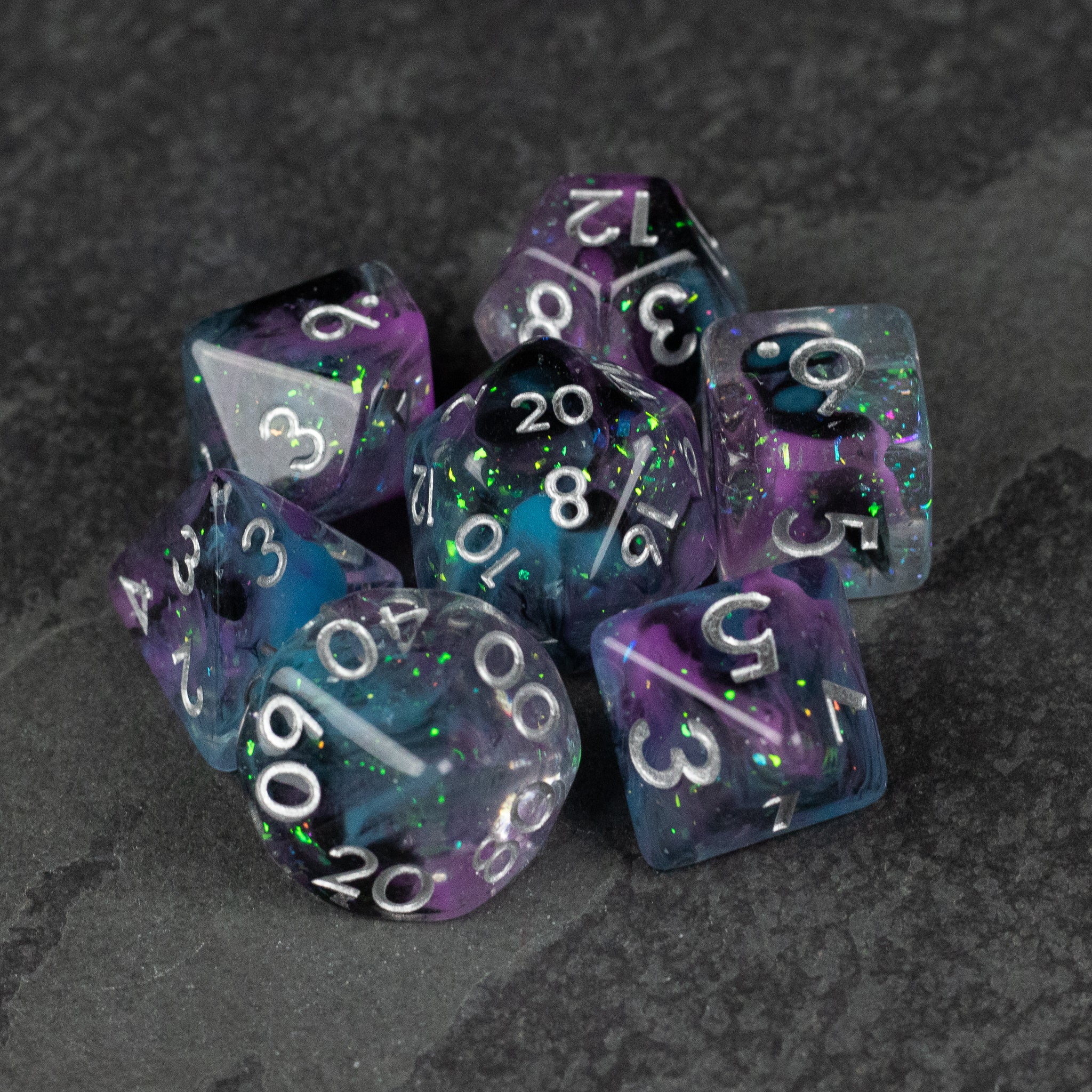 Purple and Black Spellweaver Dice Set - Seven polyhedral dice in purple and black swirl with white numbers, including a 20-sided die, arranged on a dark surface.