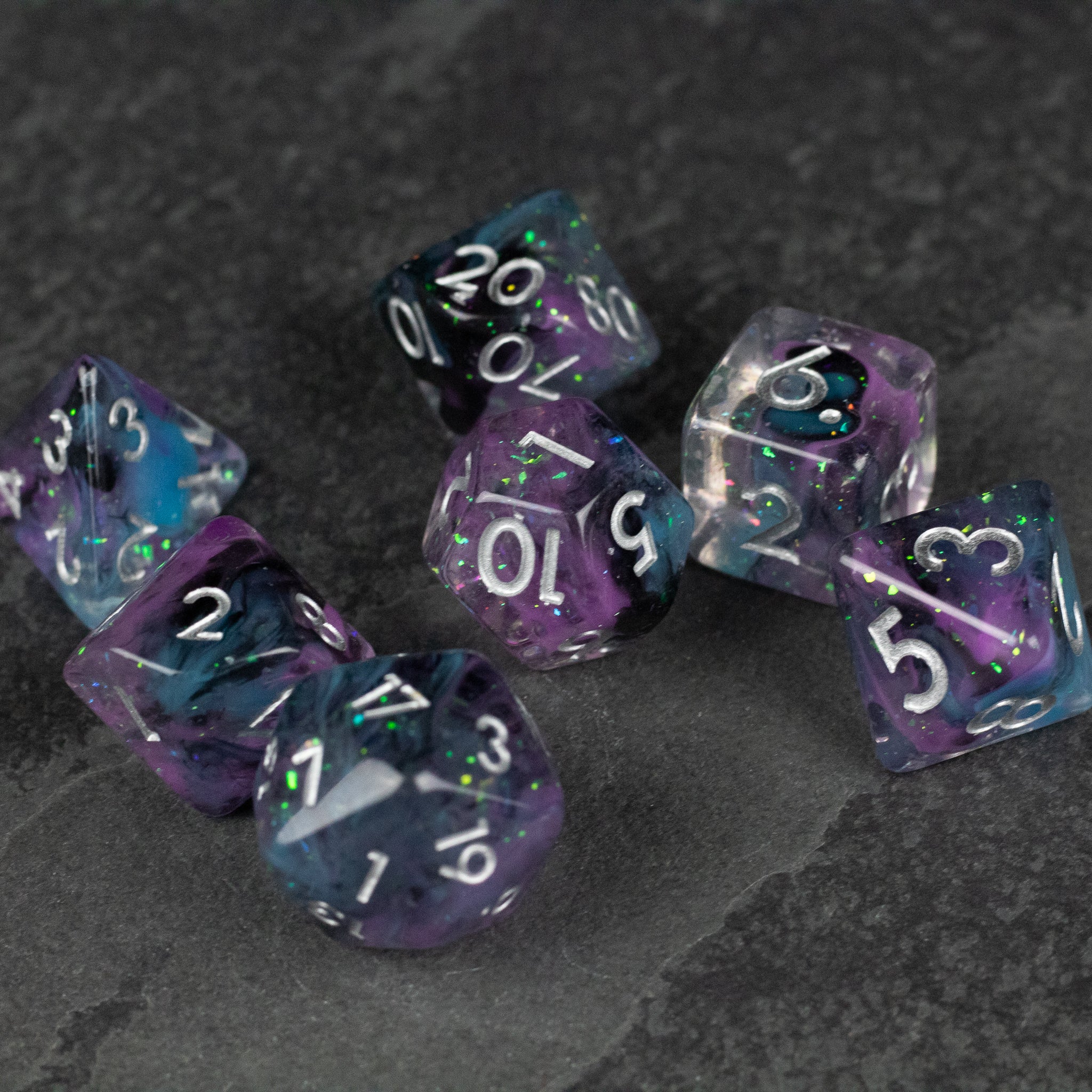 Purple and Black Spellweaver Dice Set - Translucent purple and black polyhedral dice set with white numbering on dark gray surface.
