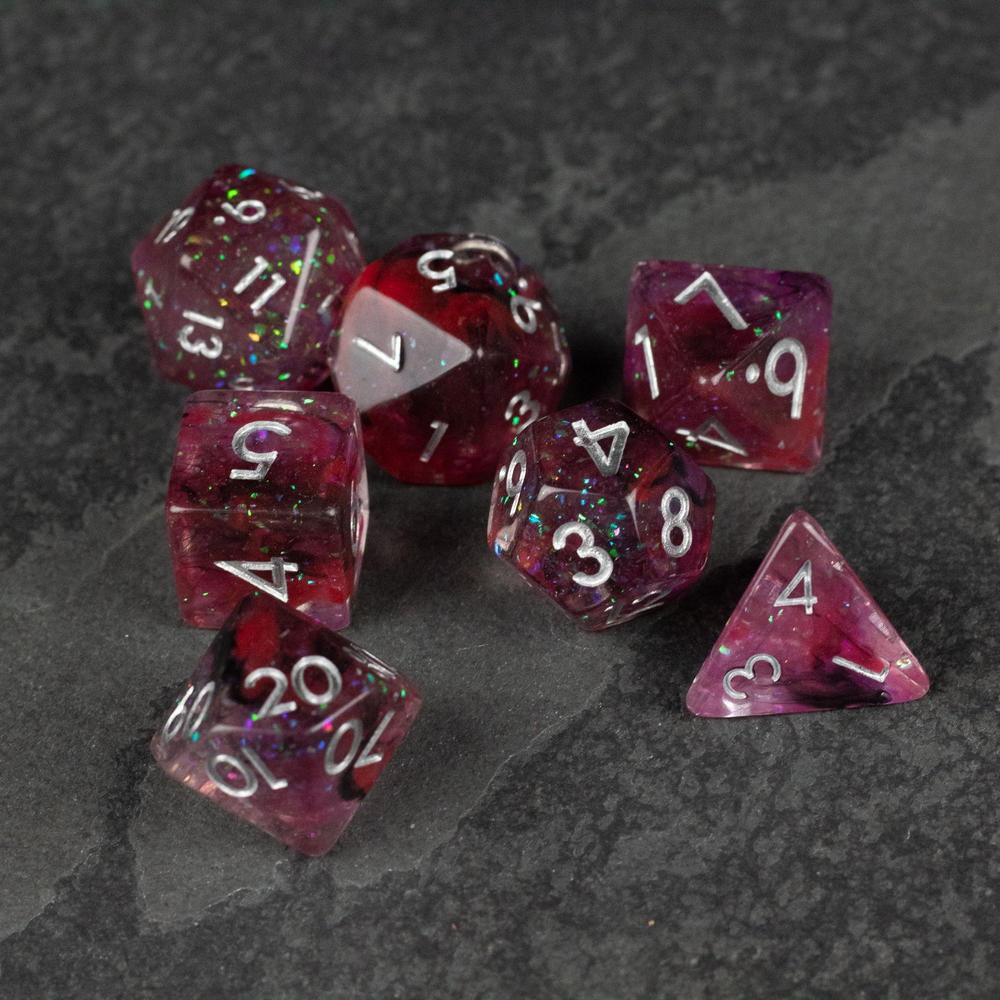 Black and red Spellweaver Dice Set - Set of seven translucent red polyhedral dice with white numbering and black speckles, including d4, d6, d8, d10, d12, and.