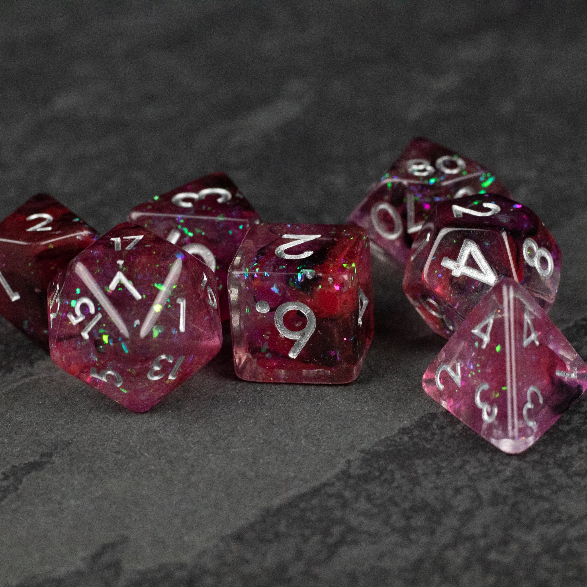 Black and red Spellweaver Dice Set - Set of translucent black and red polyhedral dice with white numbering on textured dark gray surface.