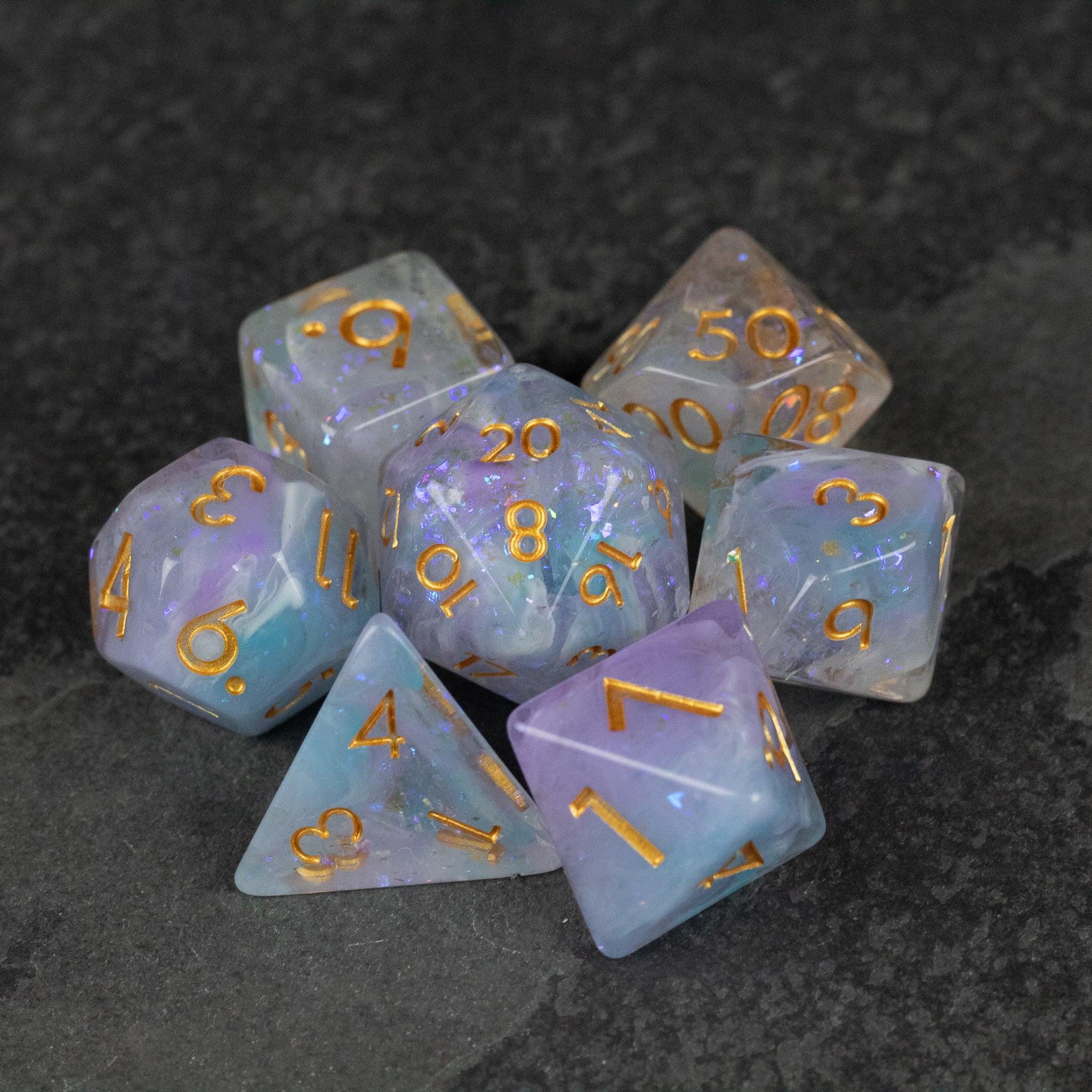 Spellbound Dice Set - Translucent purple polyhedral dice set with gold numbers, featuring shapes like d20, d12, d10, d8, d6, and d4.