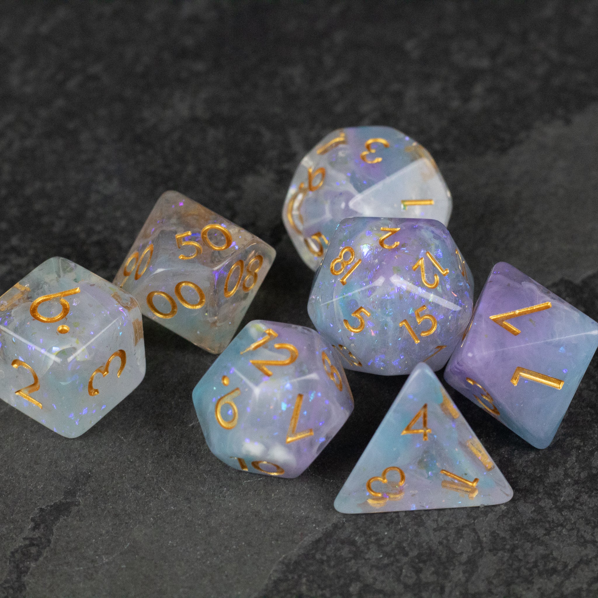 Spellbound Dice Set - Seven polyhedral dice set in translucent pastel blue and purple with gold numbering, including d4, d6, d8, d10, d12, and d20