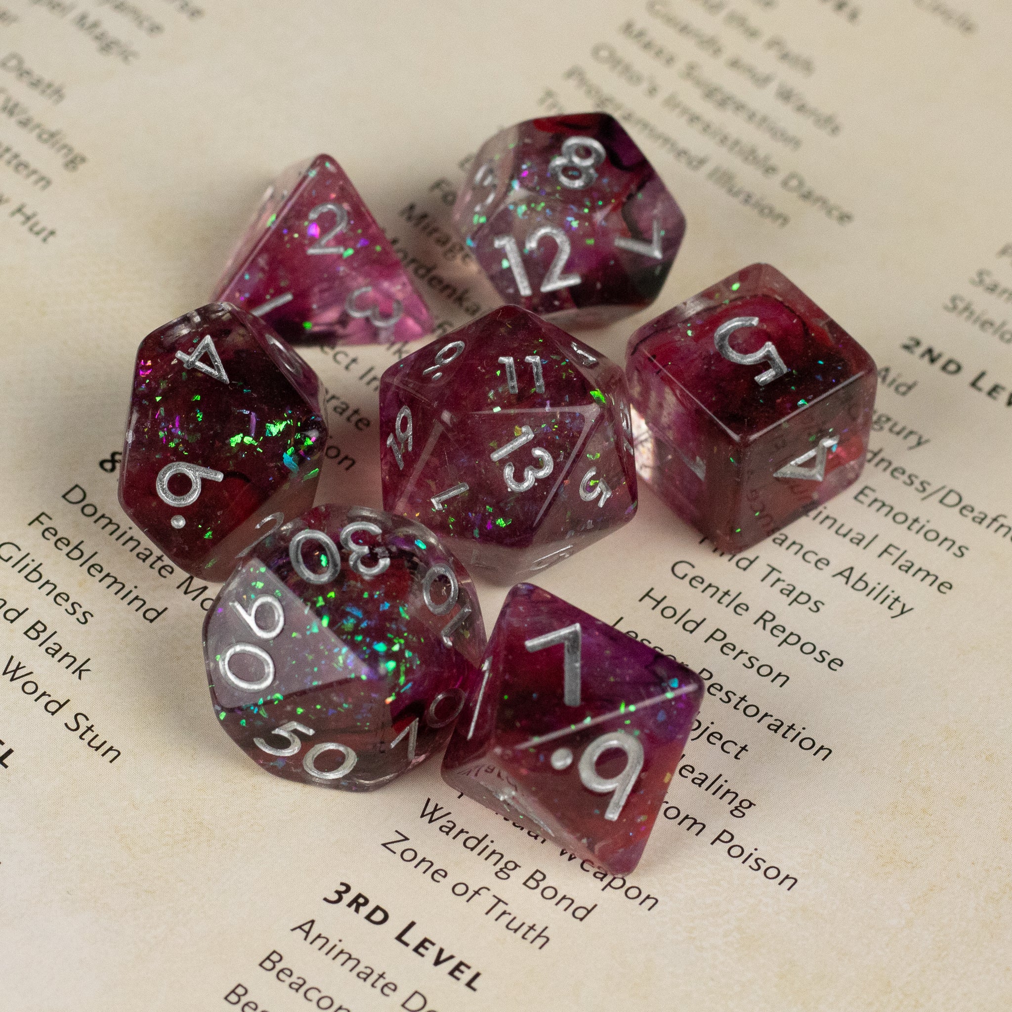 Black and red Spellweaver Dice Set - Translucent black and red polyhedral dice set with white numbering and glittery green flecks.