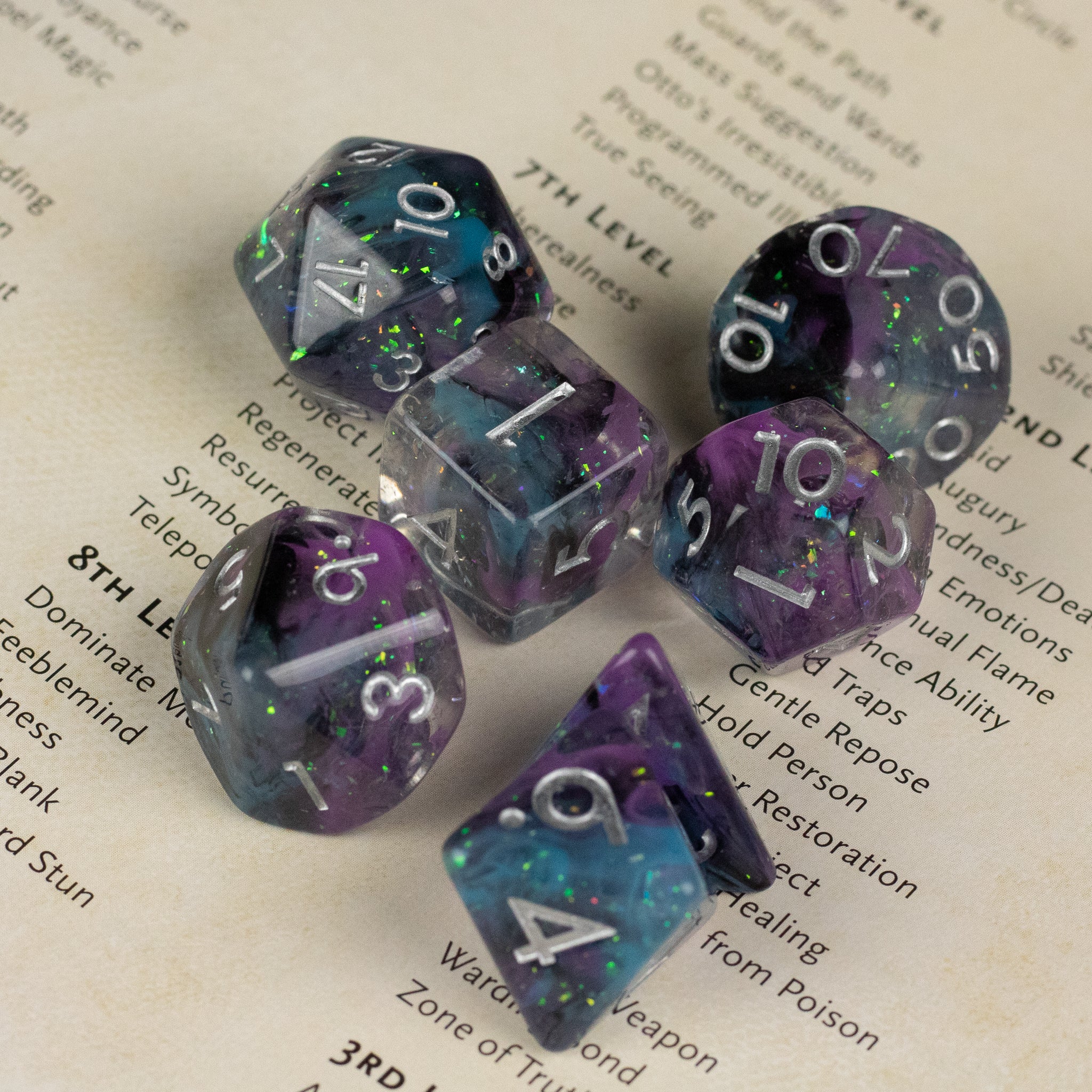 Purple and Black Spellweaver Dice Set - Set of seven translucent purple and black gaming dice with white numbering, featuring sparkly green and blue flecks inside.